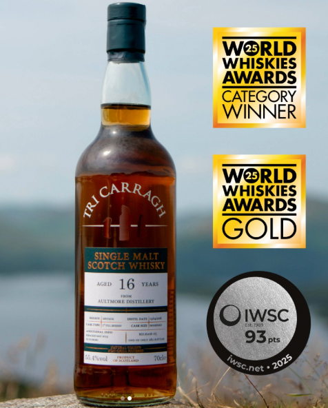 A bottle of Tri Carraigh single malt Scotch whisky with awards and a black and white IWSC medal next to it.