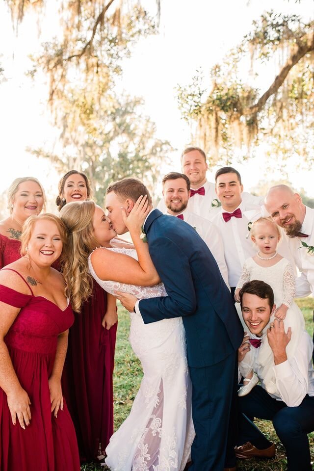 shelby and groom kiss with wedding party.jpg
