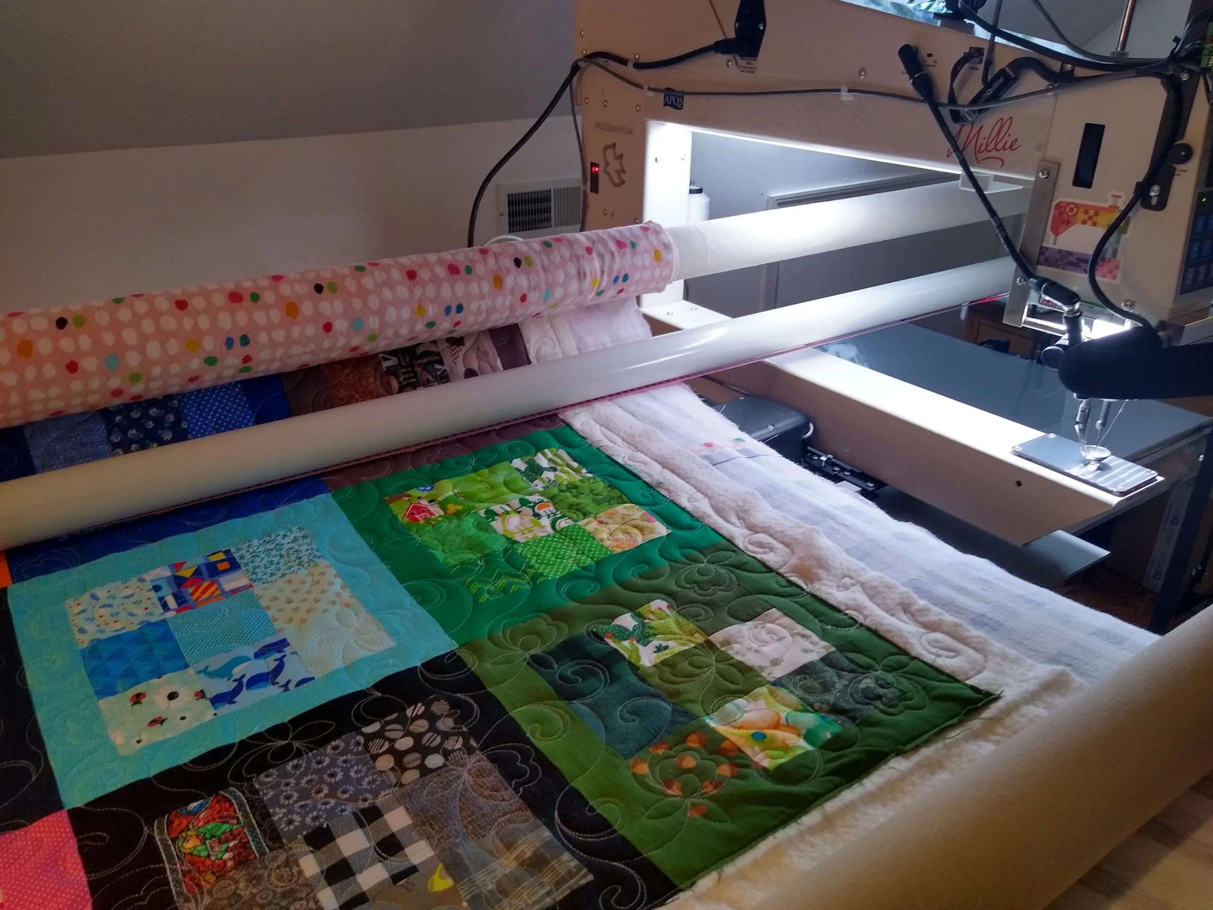 Longarm quilting machine working on a colorful patchwork quilt with intricate patterns displayed.