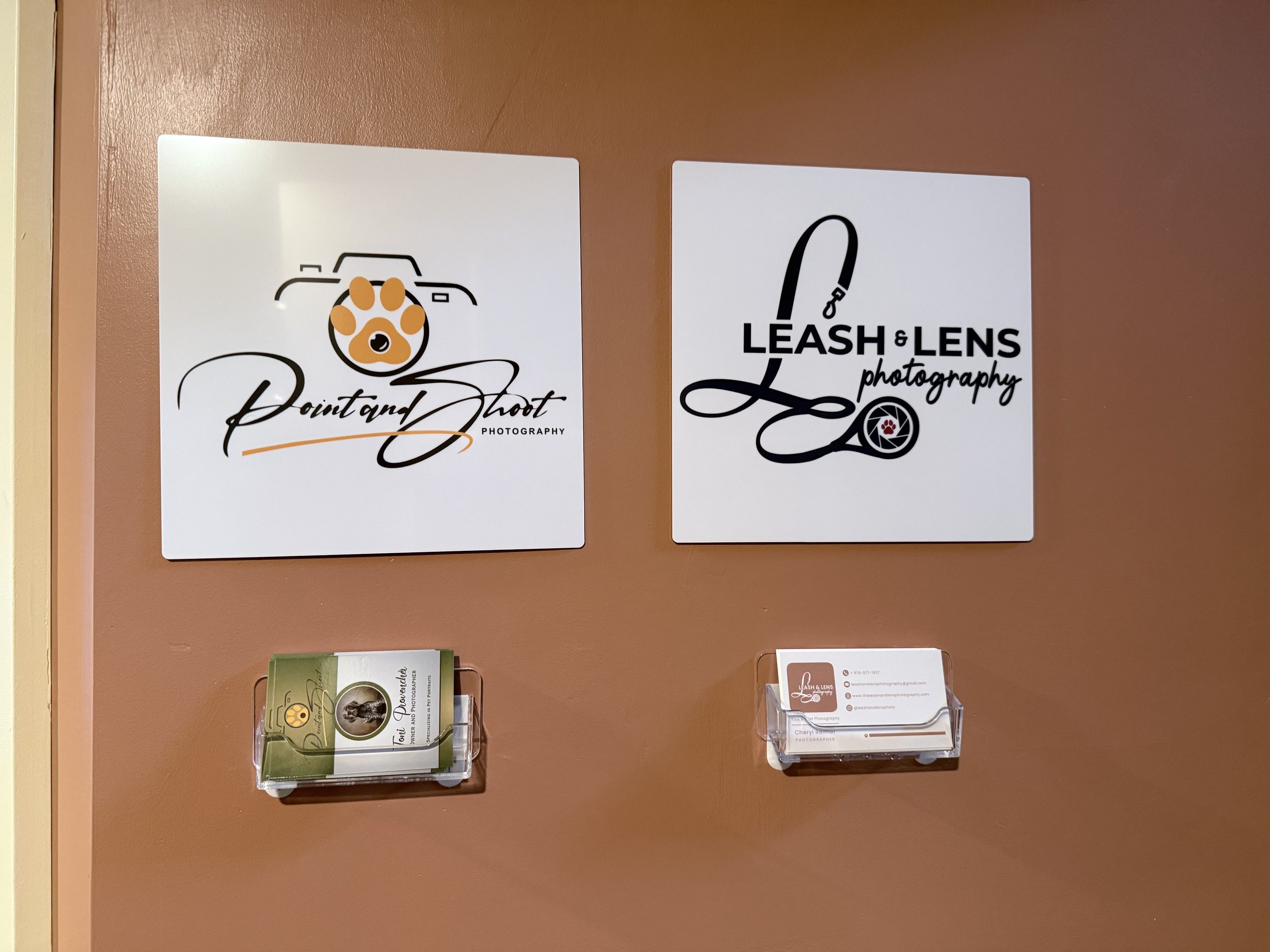 Signs for Point and Shoot Photography and Leash & Lens Photography with business cards in wall-mounted holders underneath.