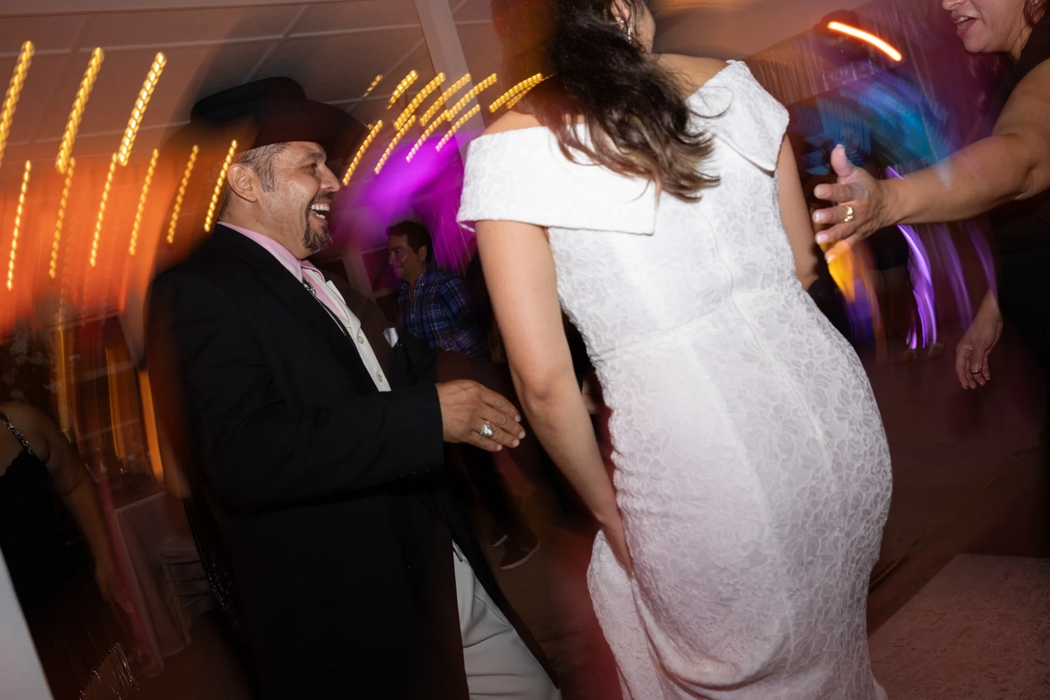 People dancing at a celebration or party with colorful lights and motion blur.