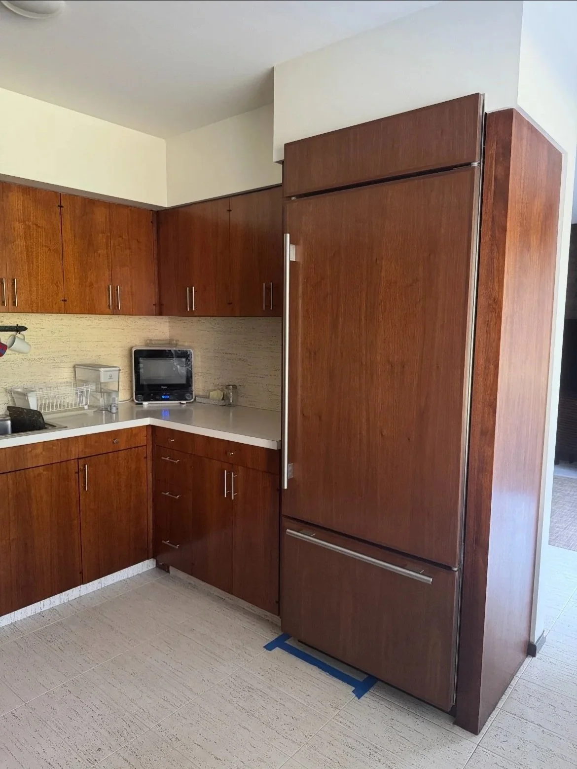 New Sub Zero refrigerator and freezer door panels in place alongside the refinished cabinet doors, drawer faces, and end panels.