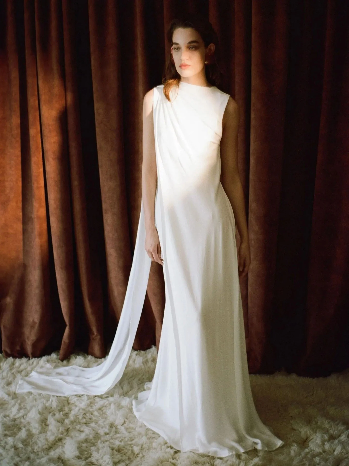 Odette &mdash; A high neck, low back silk gown with scarf detail that starts from the hip that sweeps over the shoulder to create an asymmetrical train in the back. Try Odette exclusively at The Fall Bride.
#TheFallBride