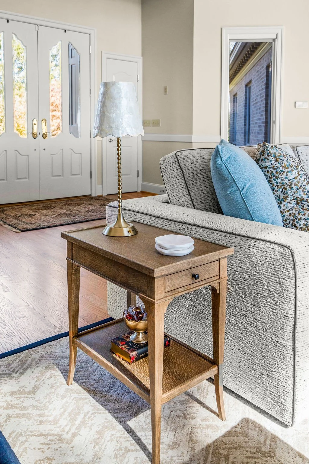 Spacious waterfront living room designed by AWH Interiors in Williamsburg, featuring soft blue accents, layered neutrals, and natural wood tones that echo the coastal surroundings.