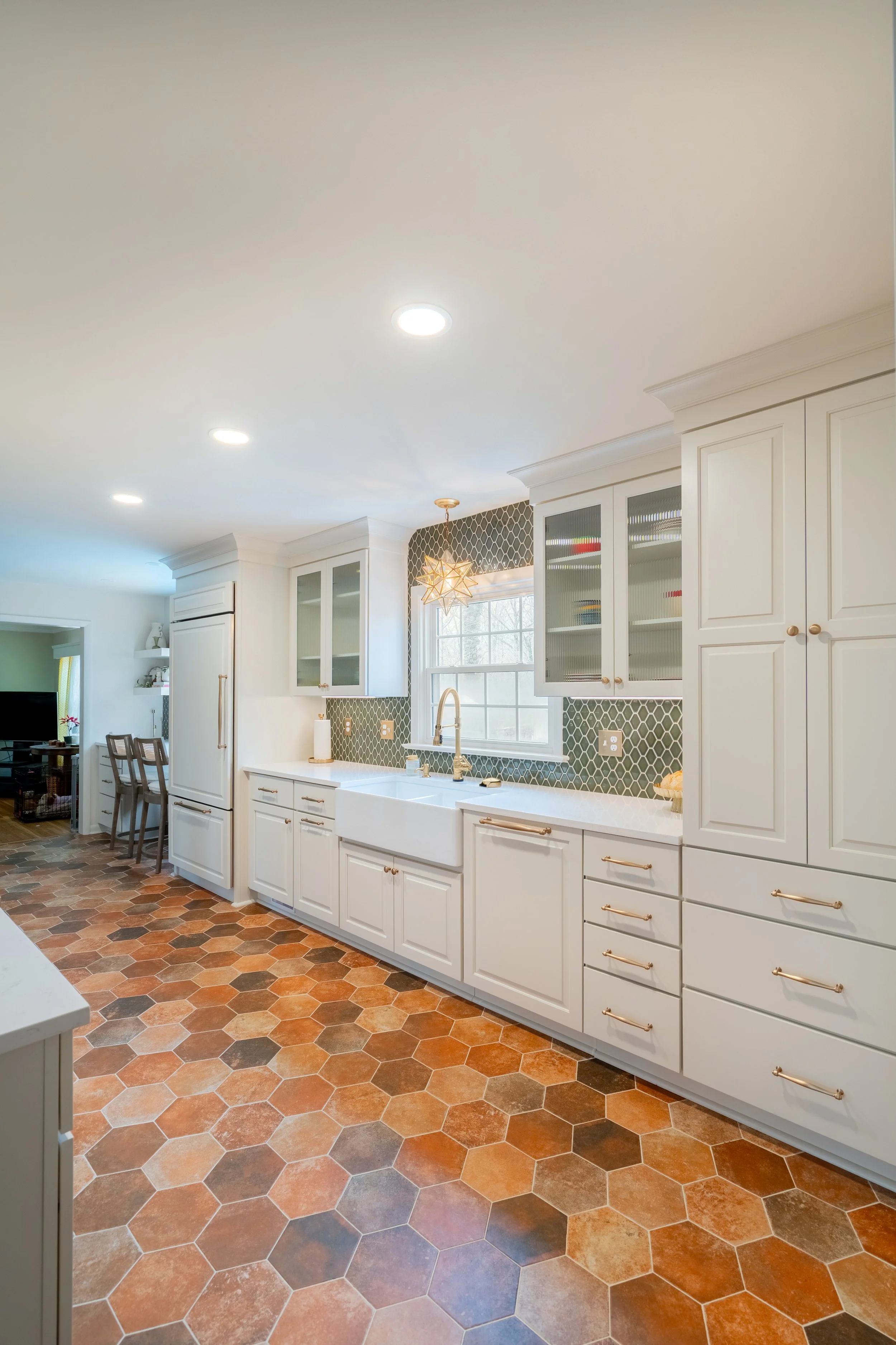 Williamsburg, VA custom galley kitchen remodel with terracotta hex tile floors, white cabinetry, chef-grade range, and brass hardware by AWH Interiors.