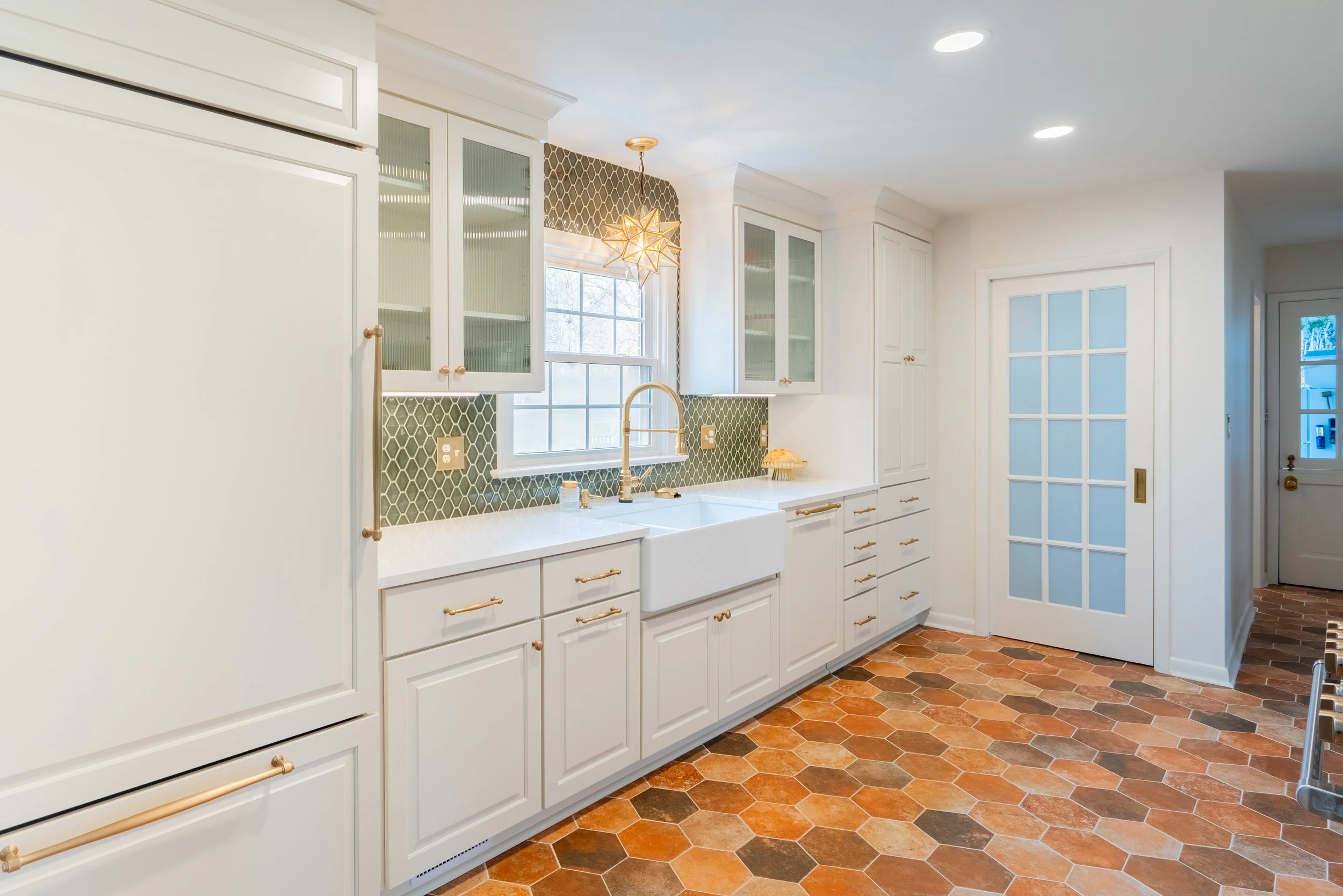 Williamsburg, VA custom galley kitchen remodel with terracotta hex tile floors, white cabinetry, chef-grade range, and brass hardware by AWH Interiors.