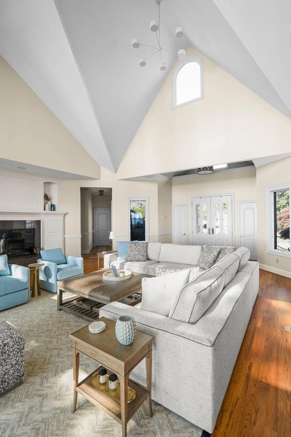 Spacious waterfront living room designed by AWH Interiors in Williamsburg, featuring soft blue accents, layered neutrals, and natural wood tones that echo the coastal surroundings.