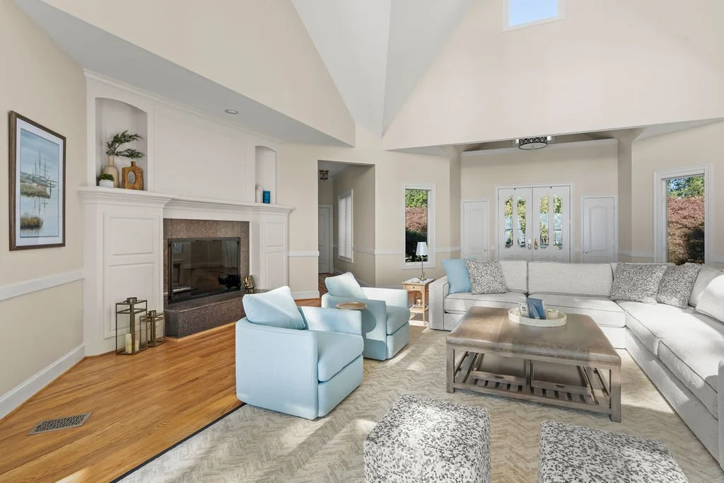 Spacious waterfront living room designed by AWH Interiors in Williamsburg, featuring soft blue accents, layered neutrals, and natural wood tones that echo the coastal surroundings.