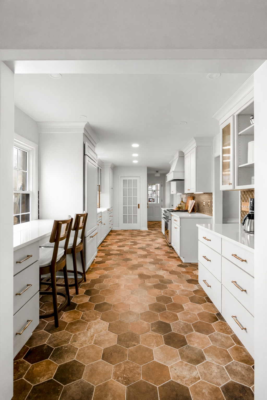 Williamsburg, VA custom galley kitchen remodel with terracotta hex tile floors, white cabinetry, chef-grade range, and brass hardware by AWH Interiors.