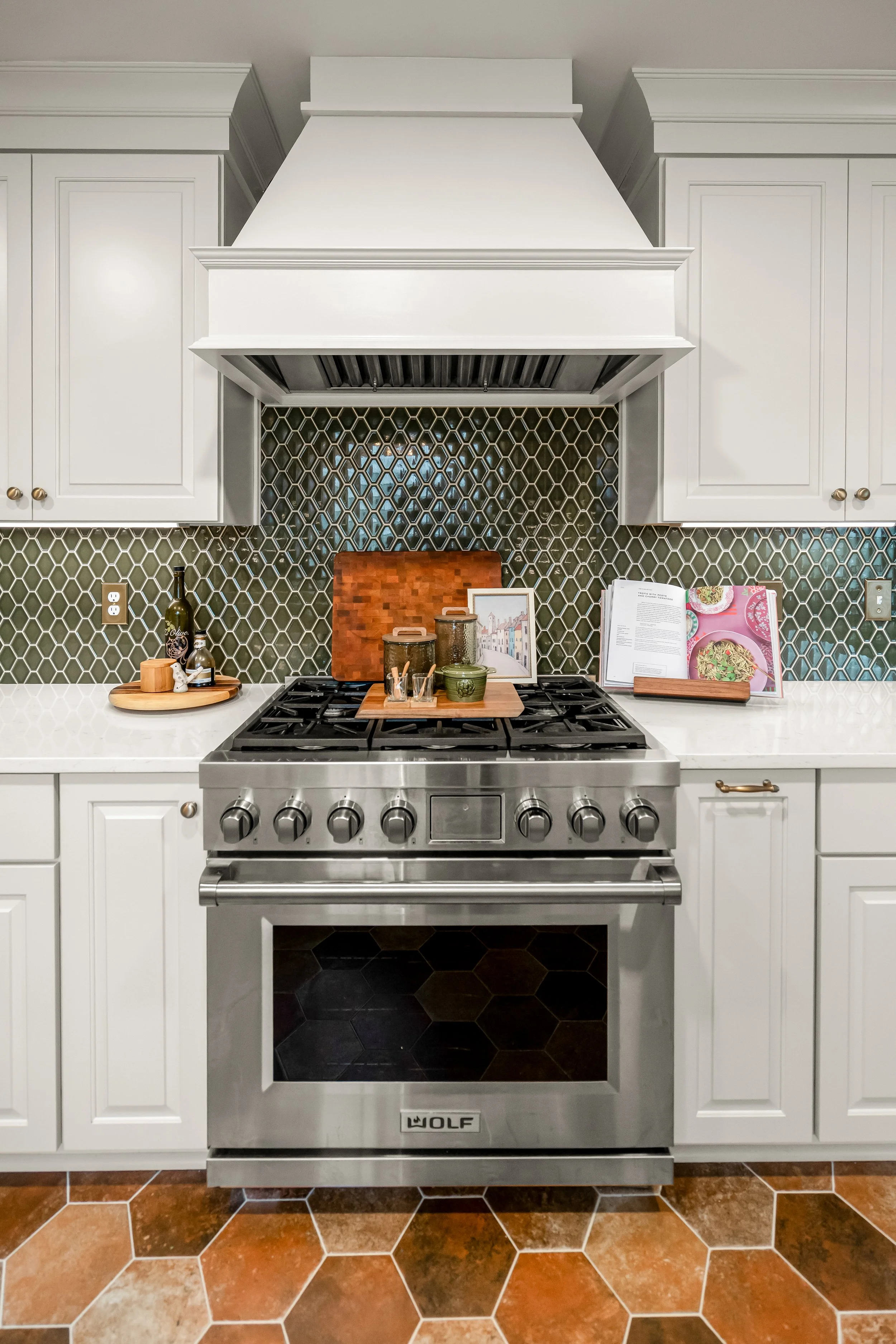 Williamsburg, VA custom galley kitchen remodel with terracotta hex tile floors, white cabinetry, chef-grade range, and brass hardware by AWH Interiors.