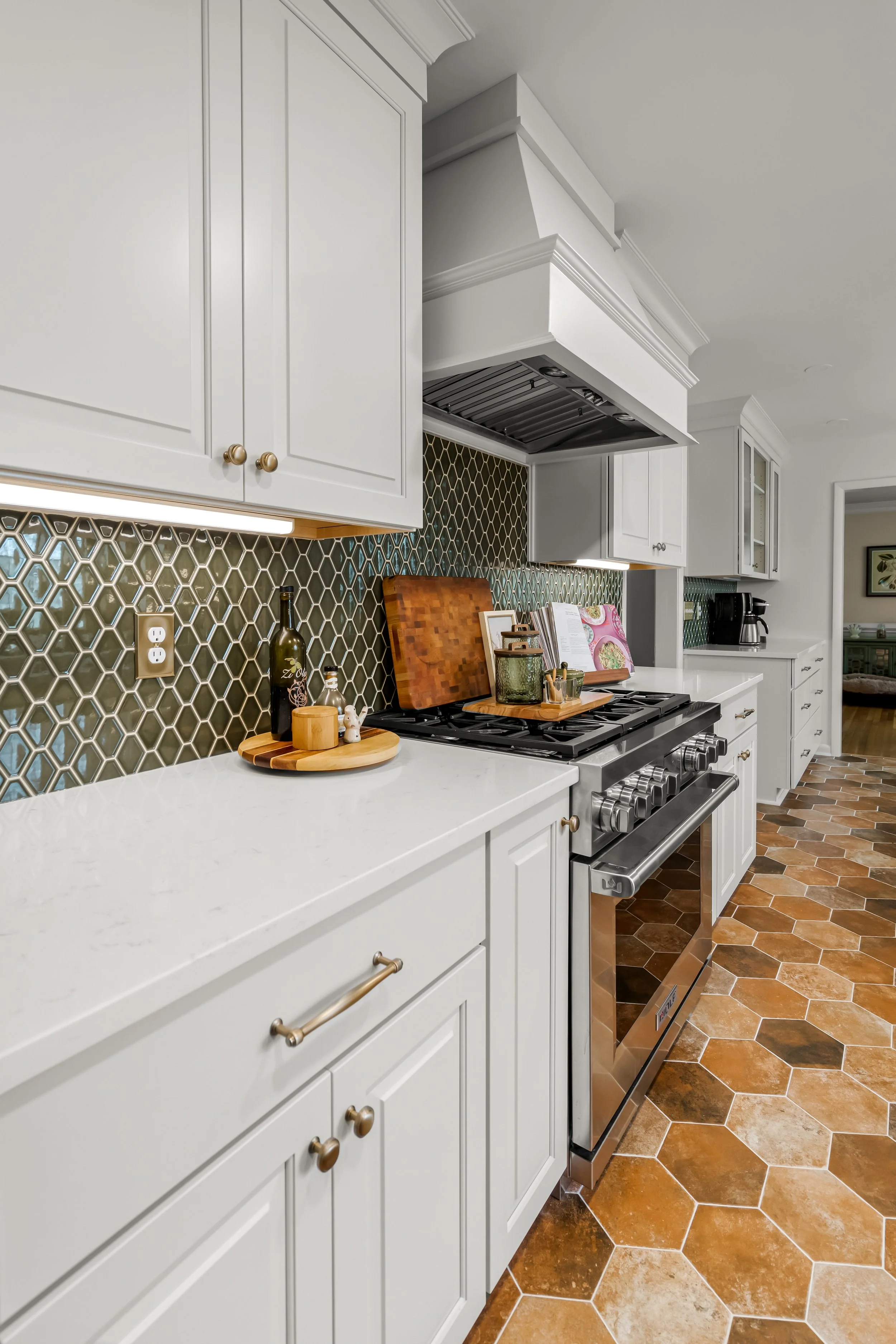 Williamsburg, VA custom galley kitchen remodel with terracotta hex tile floors, white cabinetry, chef-grade range, and brass hardware by AWH Interiors.