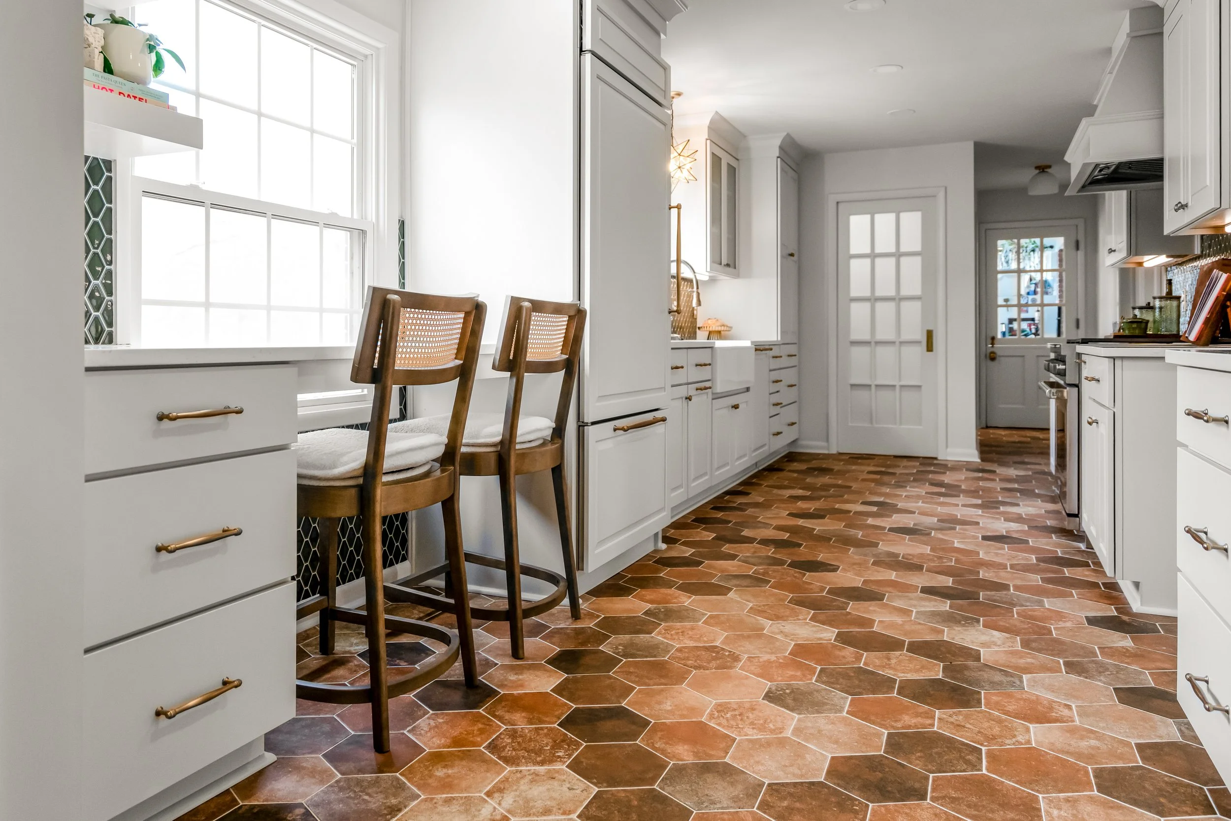 Breakfast bar in a Williamsburg, Virginia kitchen remodel overlooking the backyard, with custom cabinetry and paneled appliances by AWH Interiors.