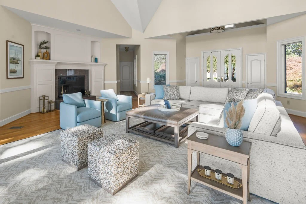 Spacious waterfront living room designed by AWH Interiors in Williamsburg, featuring soft blue accents, layered neutrals, and natural wood tones that echo the coastal surroundings.