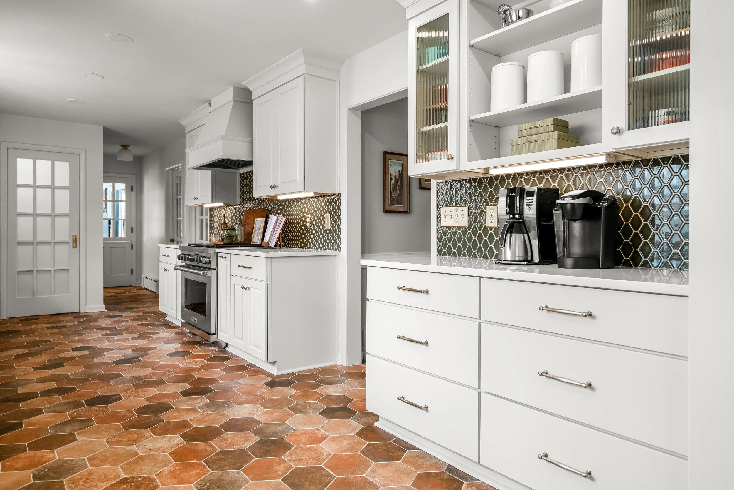 Williamsburg, VA custom galley kitchen remodel with terracotta hex tile floors, white cabinetry, chef-grade range, and brass hardware by AWH Interiors.