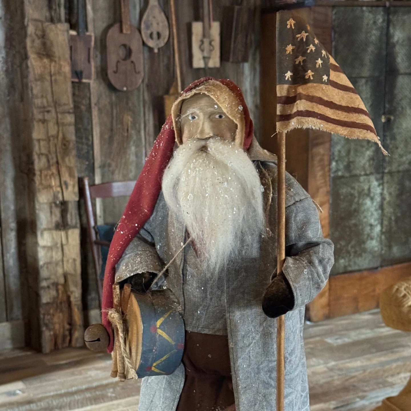 2026 Santa wearing a gray coat with a drum and flag