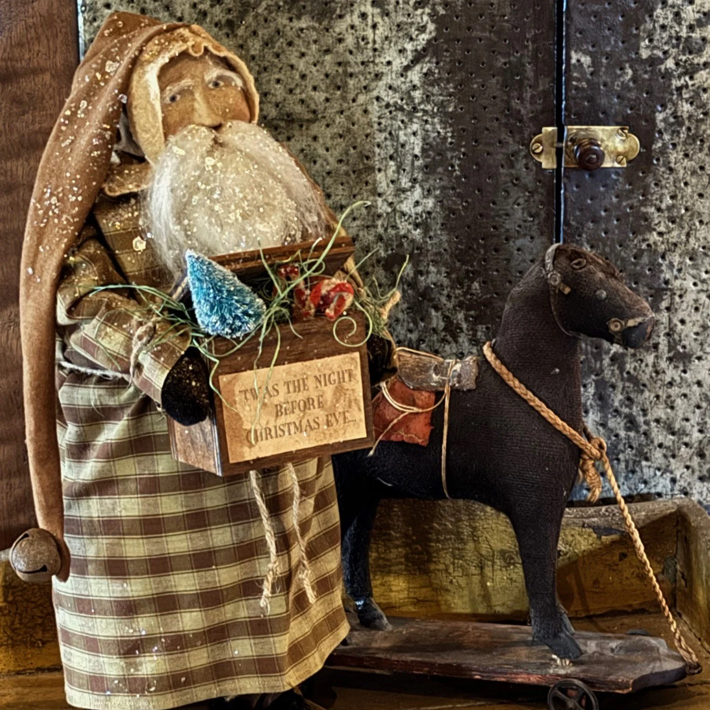 2026 Santa wearing a brown homespun coat holding a toy box