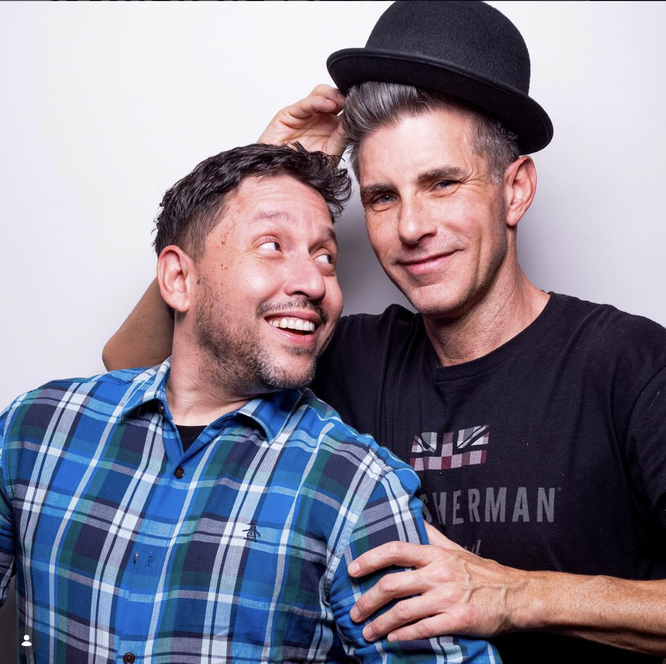 Alex and Rick Ferrari posing with a neutral background and a black bowler hat