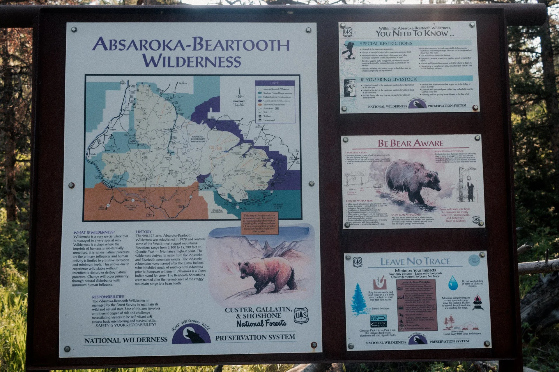 Information board for Absaroka-Beartooth Wilderness with a map, guidelines, and safety tips about bears and wilderness preservation, including images of a bear and a hiker.