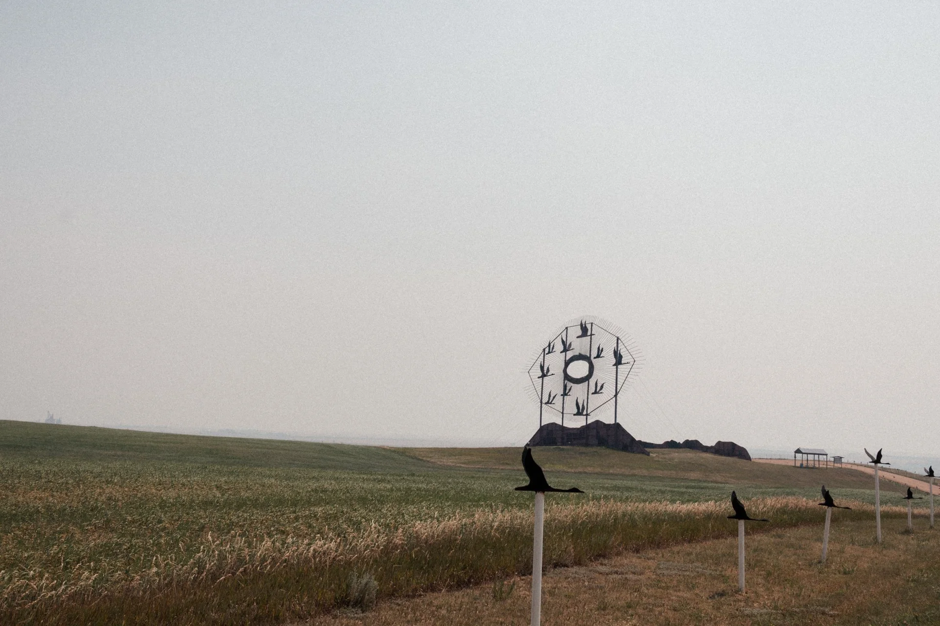 Open field with silos and modern wind turbines, cloudy sky, daytime.
