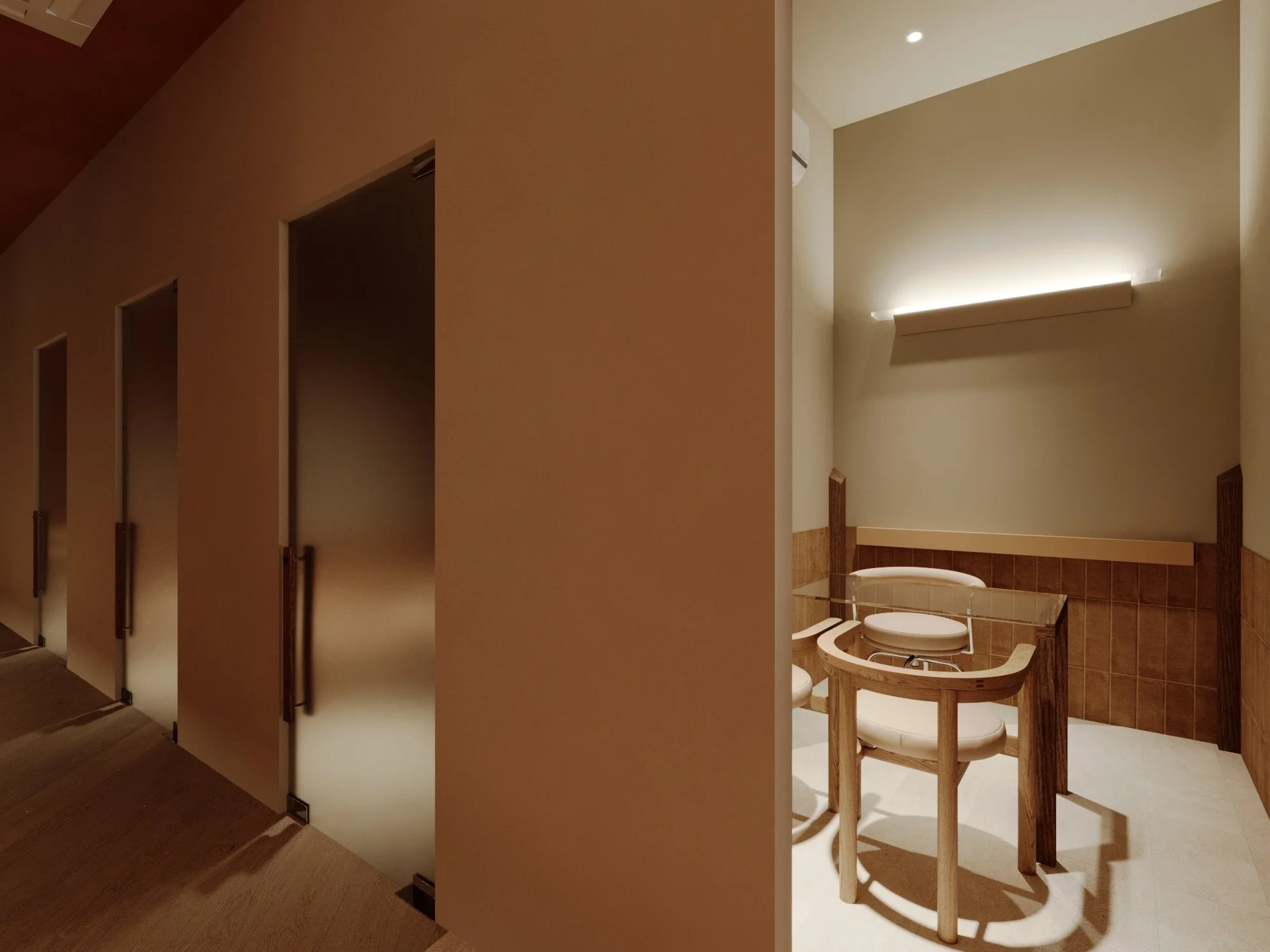 A restroom with a toilet and a chair, divided from hallway with individual stalls, well-lit with warm lighting.
