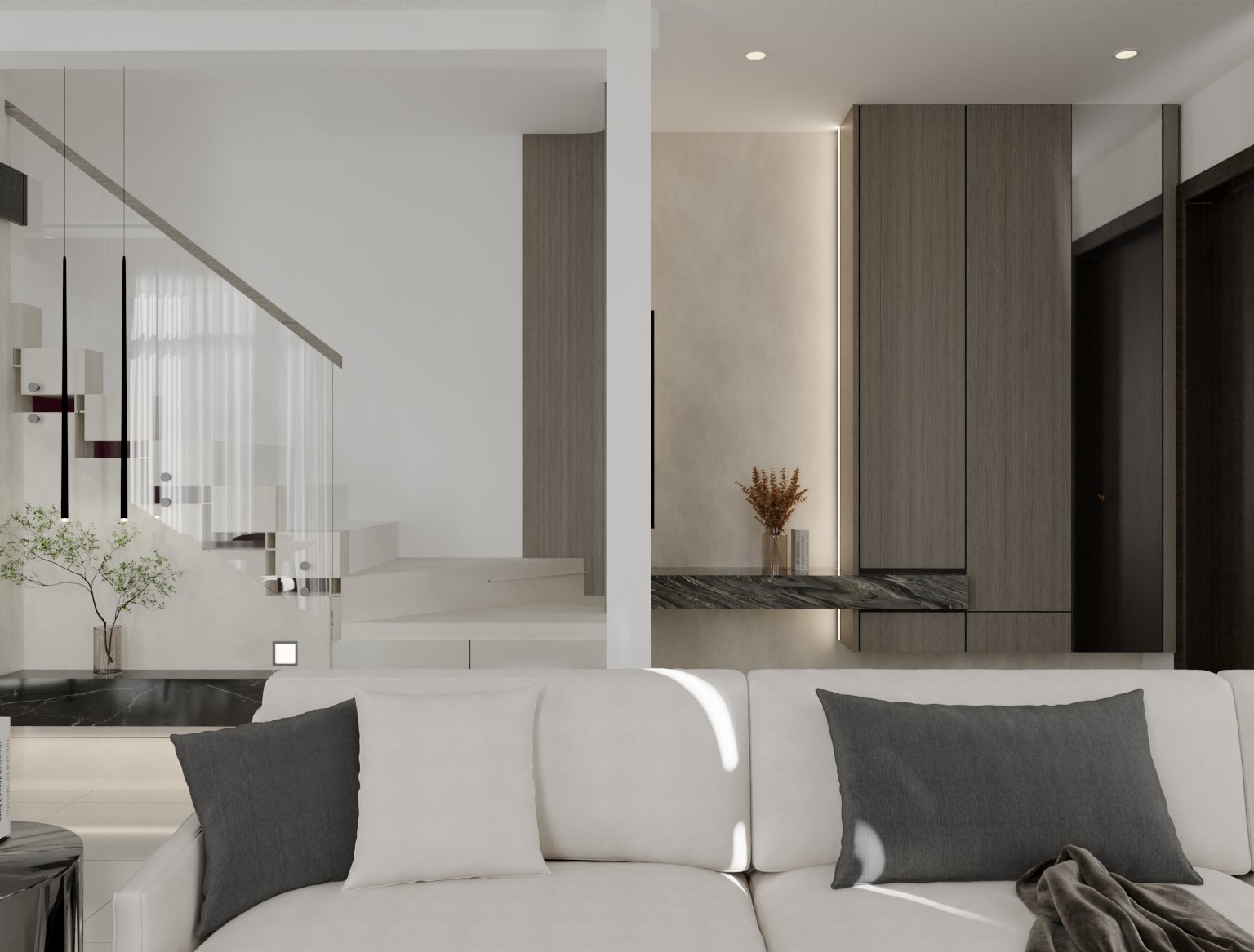 Modern living room with a white sofa and gray pillows, situated in front of a wall with wooden panels, a small vase with dried flowers, and a marble shelf, with a staircase featuring black pendant lights and a white railing in the background.