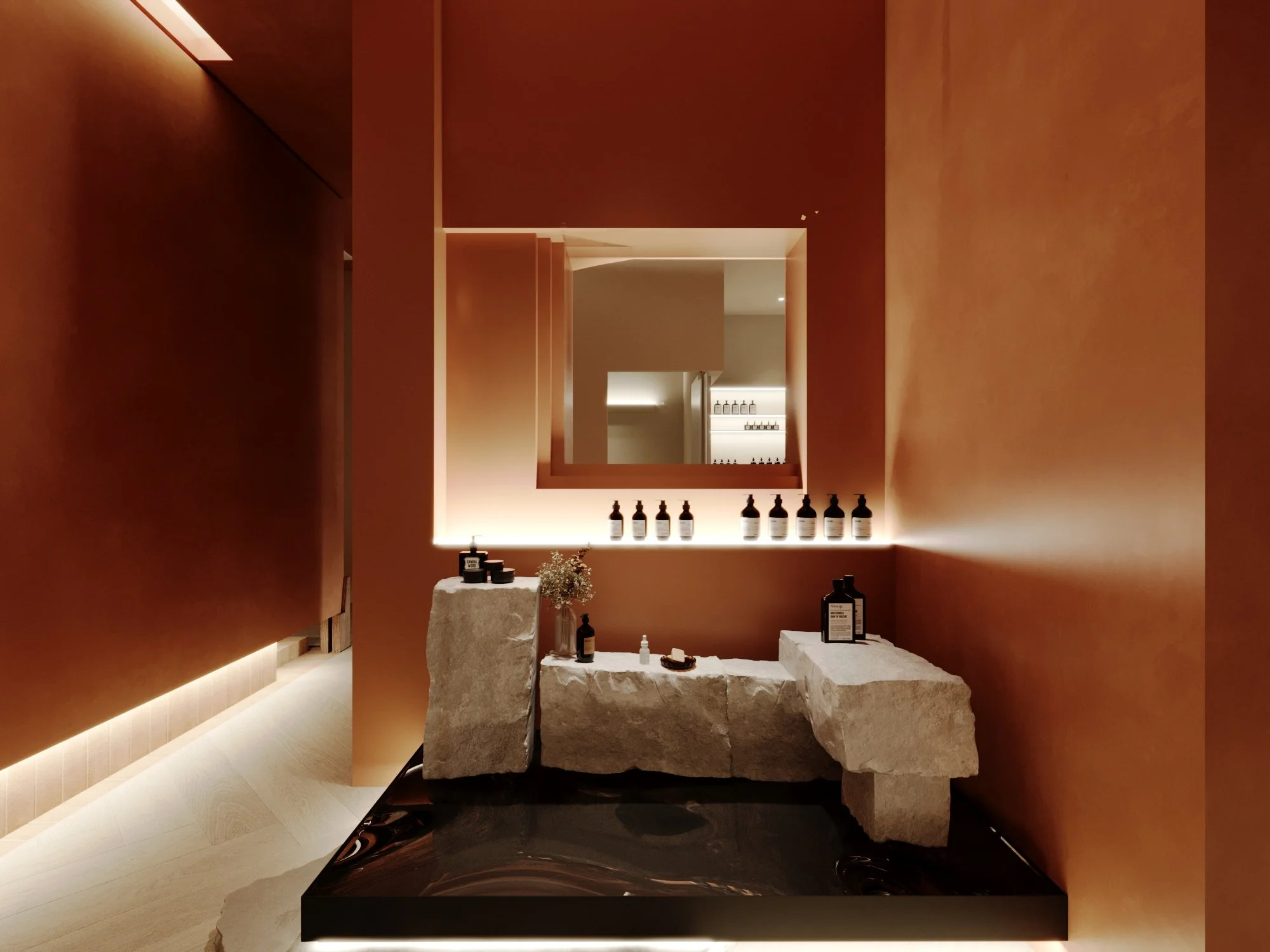Modern interior with warm orange walls, a mirror with backlit frame, and a stone sculpture display with bottles and small objects on a black platform.