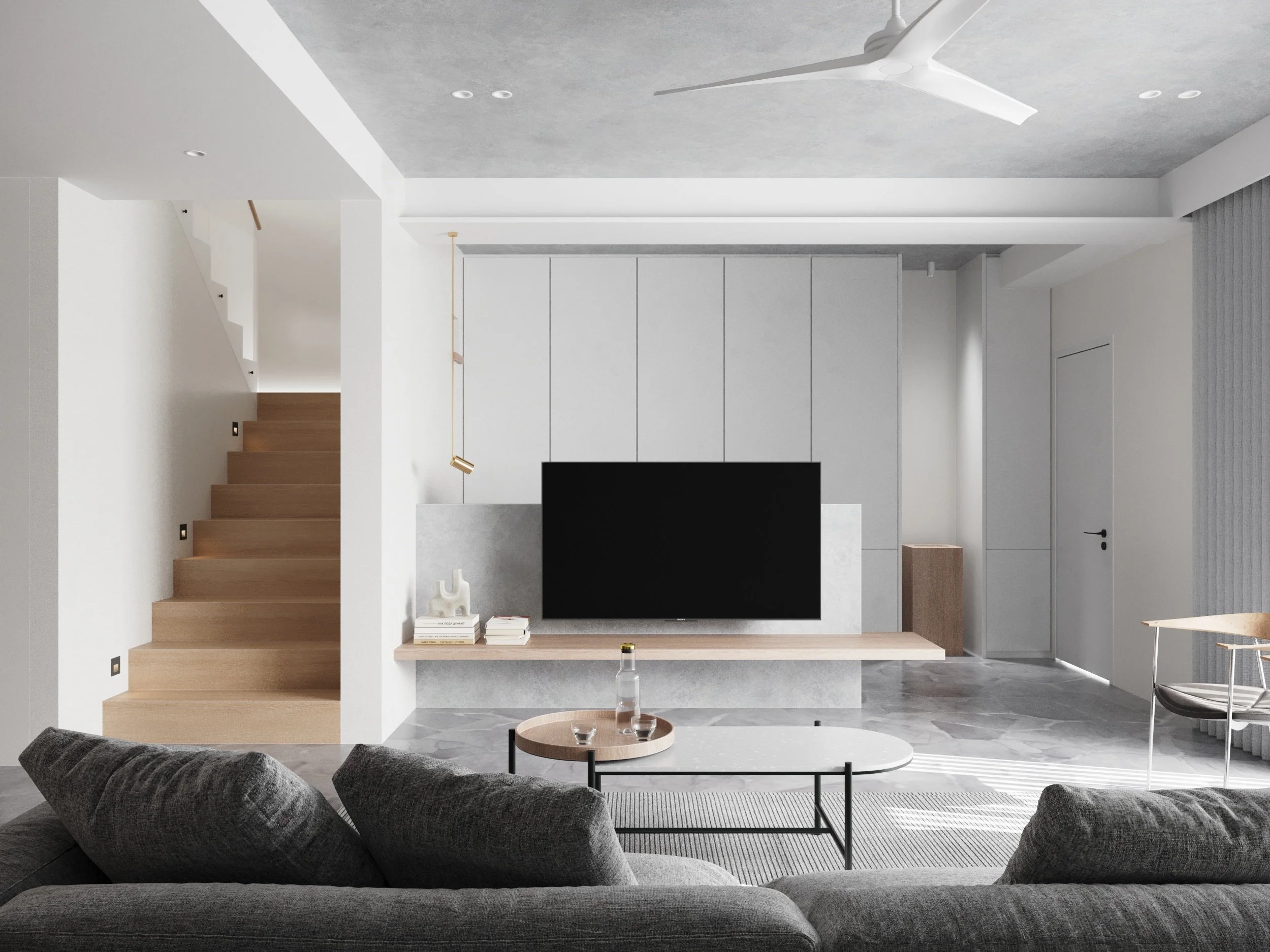 Modern living room with gray sofa, coffee tables, wall-mounted TV, and staircase with wooden steps.