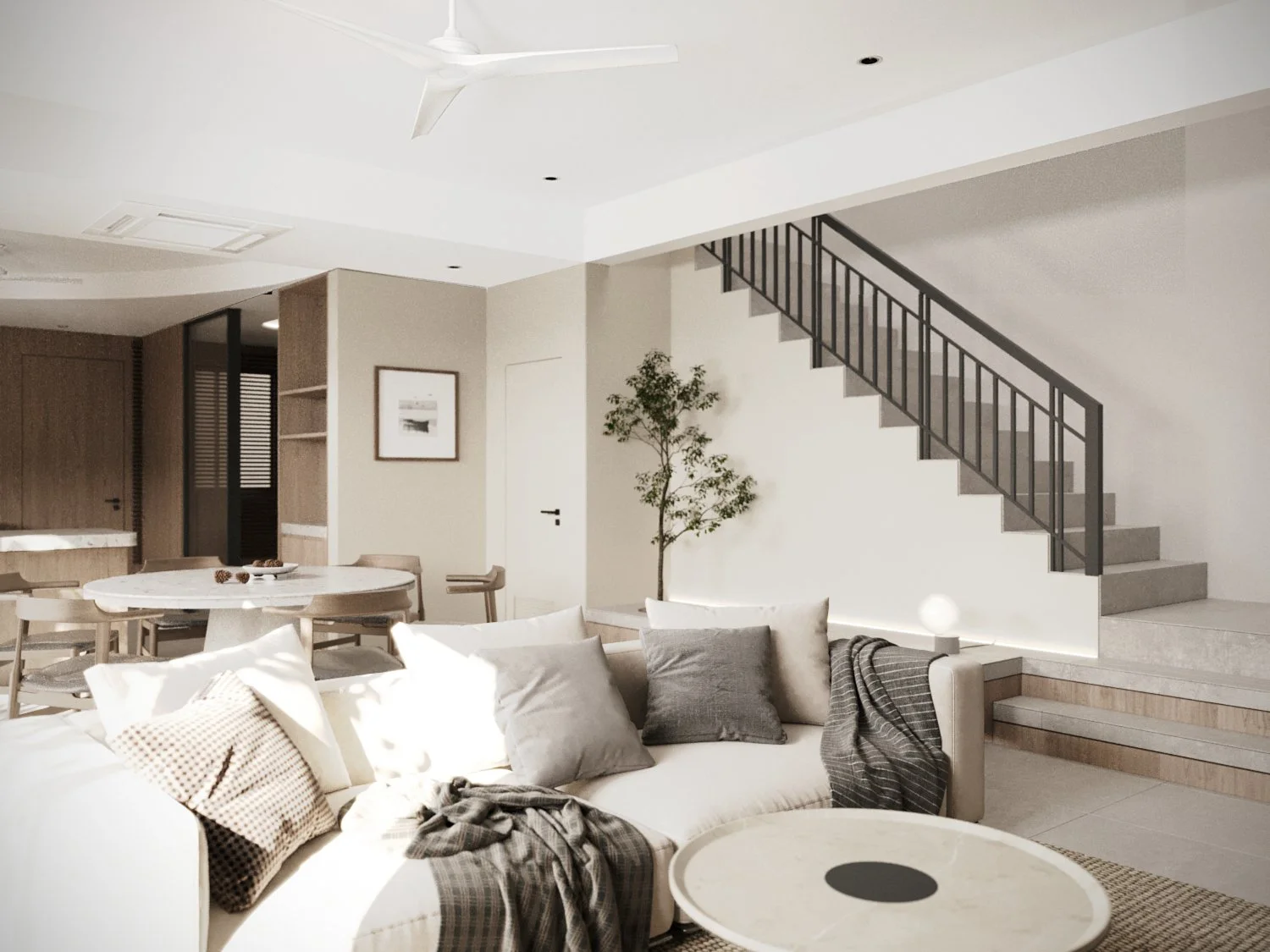 Modern living room with white sofa, gray pillows, throw blanket, round coffee table, staircase with black railing, small potted tree, wall art, and dining area in background.