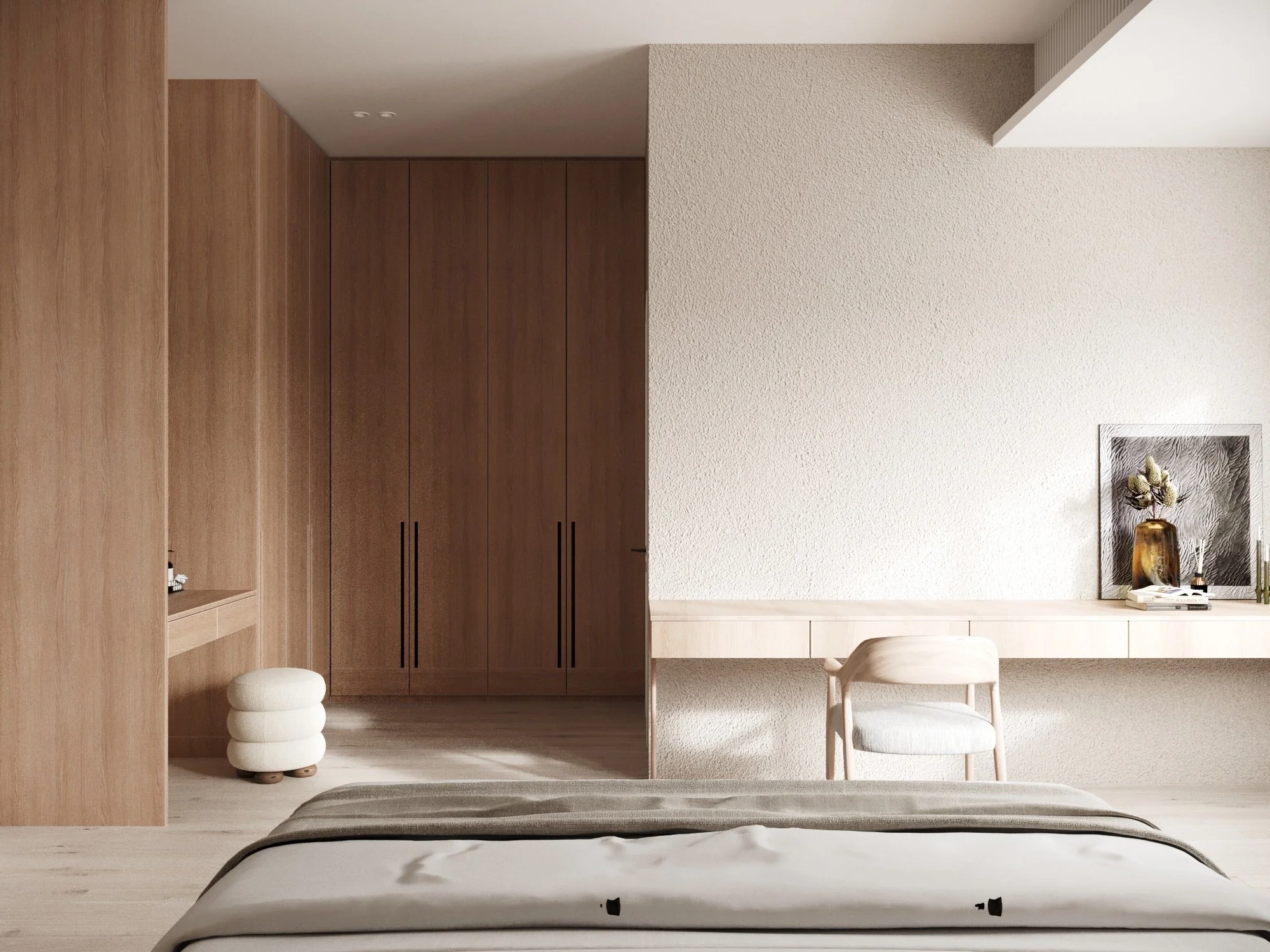 Minimalist bedroom with a bed, a built-in wooden wardrobe, a small upholstered stool, a desk with a chair, and decorative items including a framed artwork, a vase with flowers, and books.