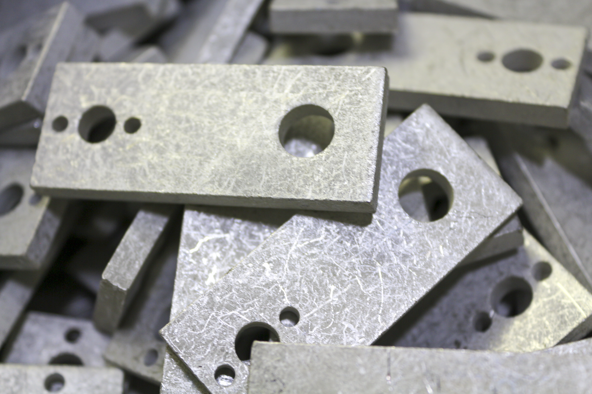 Several rectangular metal blocks with circular holes, piled together.