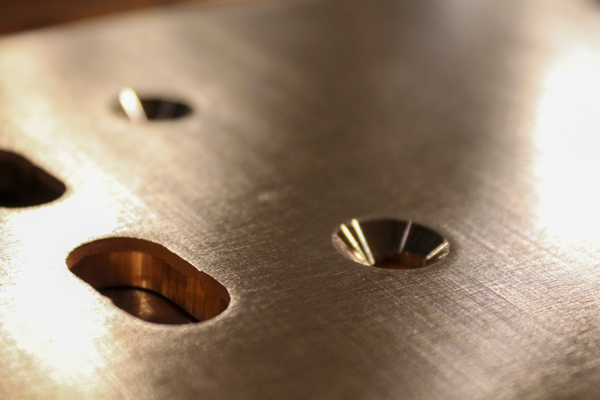 Close-up view of a metallic surface with multiple circular and elongated holes