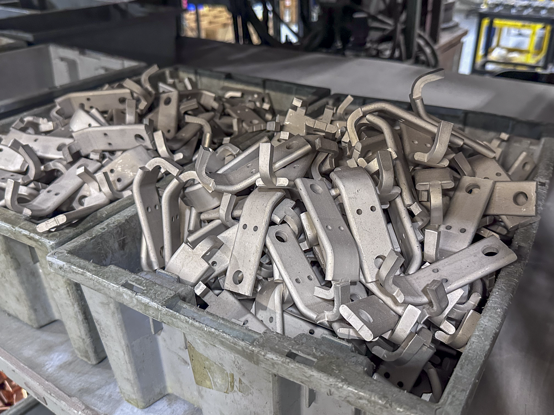 Collection of metal clips or brackets in a large container, in an industrial setting.