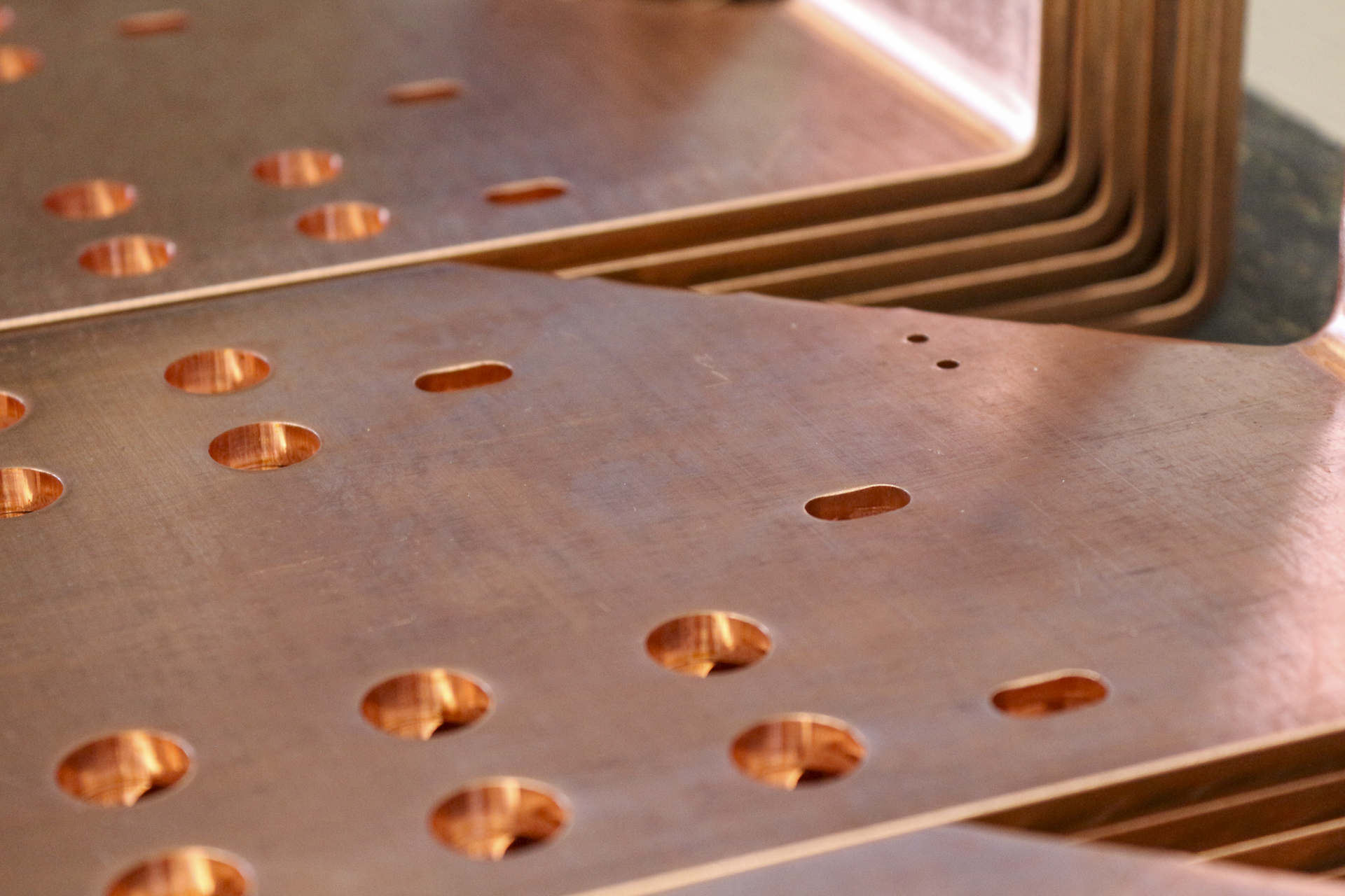 Stacked copper sheets with round and oval holes.