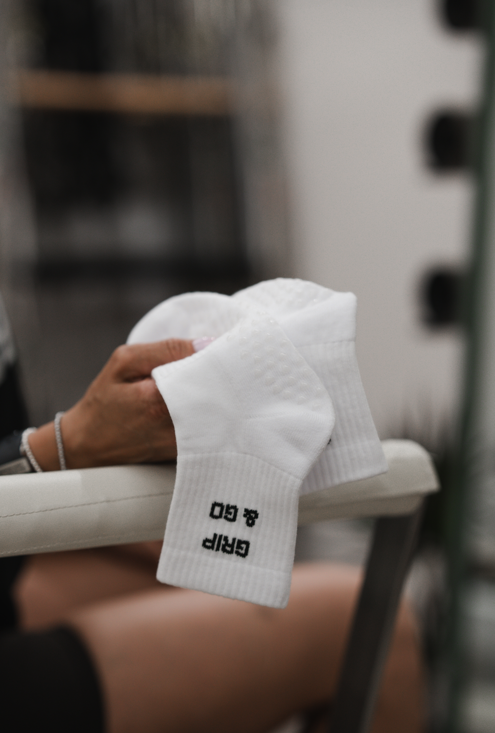 A hand holding white socks with black text reading 'GAP 8.0', on a surface in a retail or laundry setting.