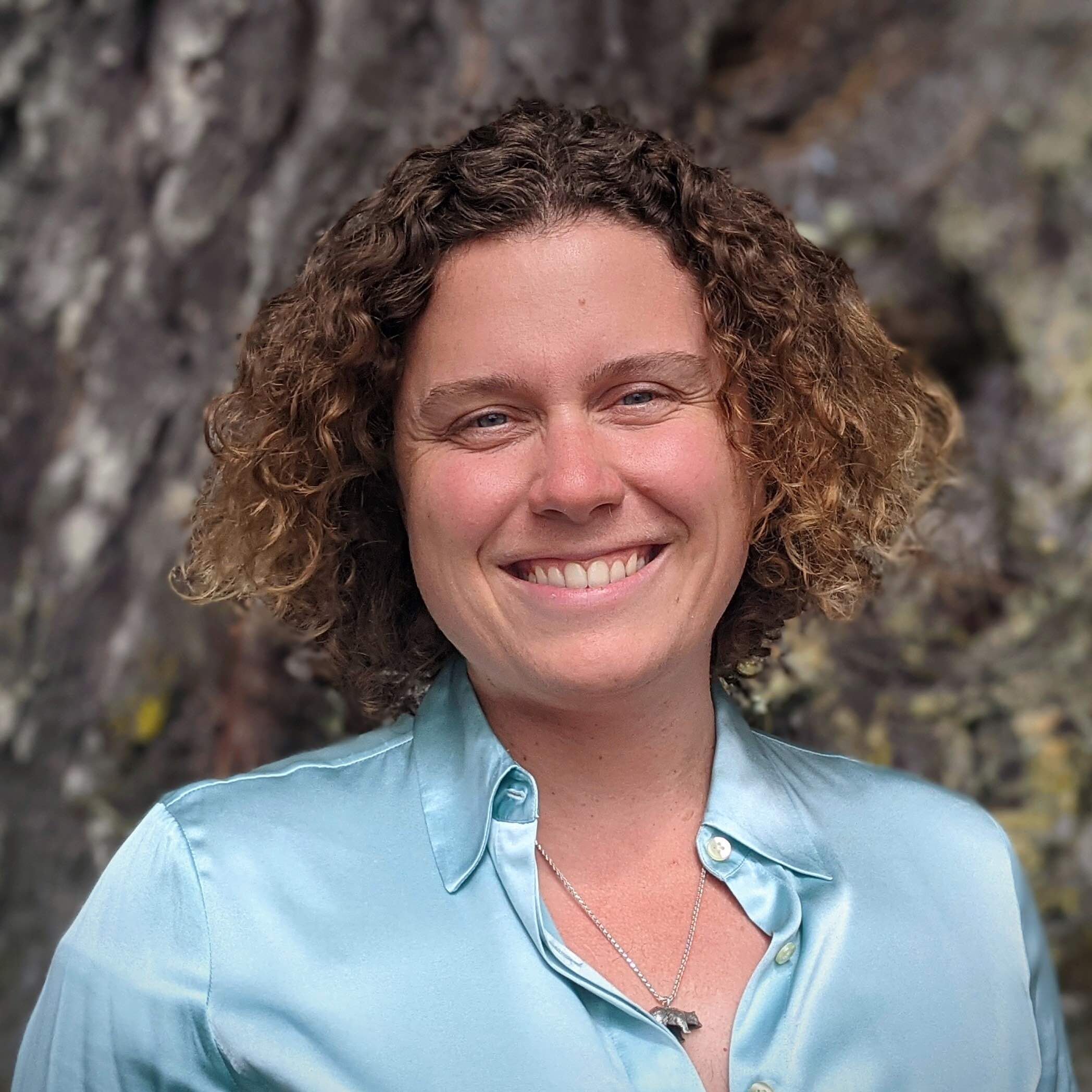 Frances Sawyer smiling and wearing a blue shirt, with a tree in the background