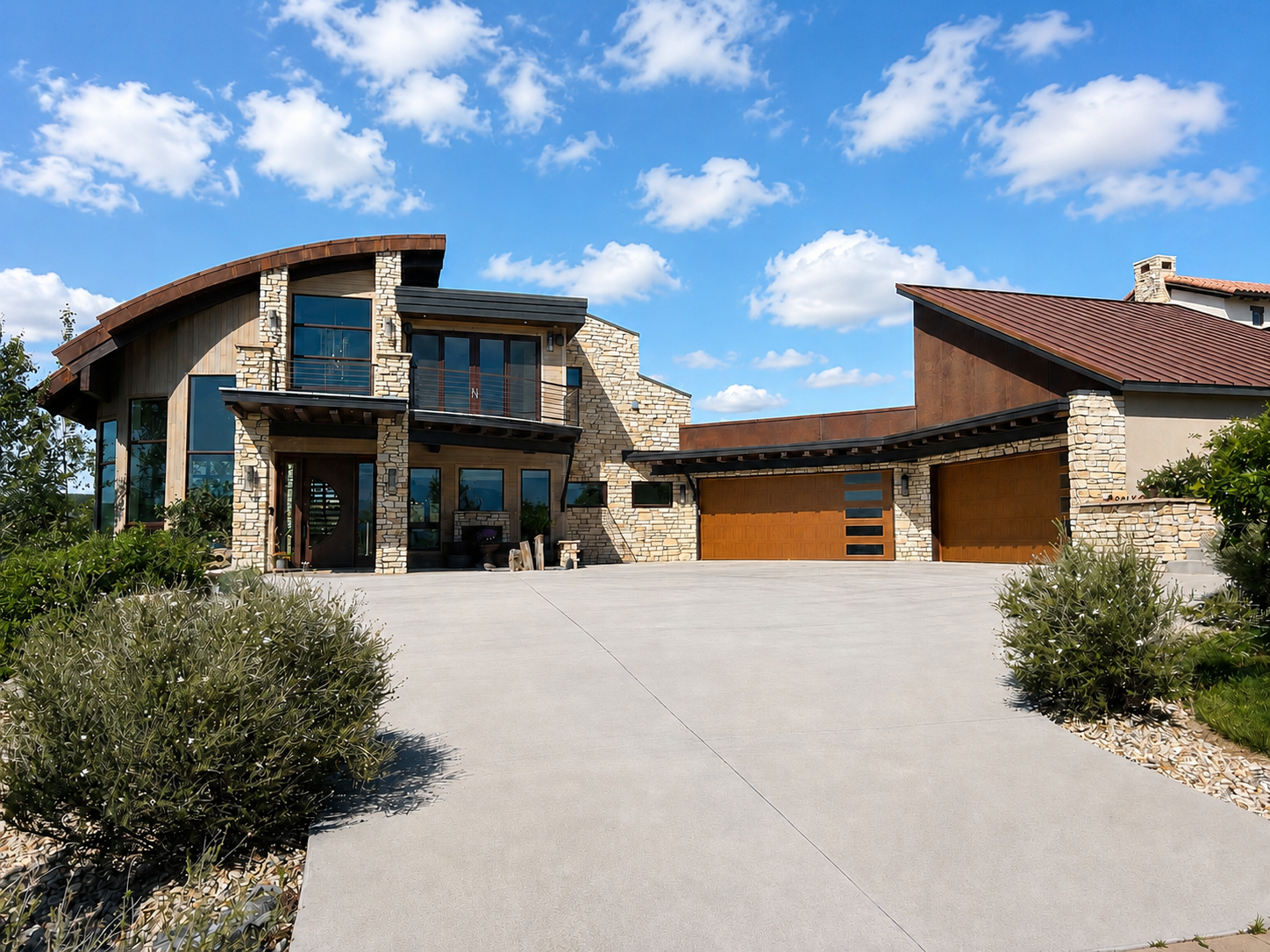 Modern white house with gray roof, front yard with green grass, two gray garage doors, surrounded by trees.