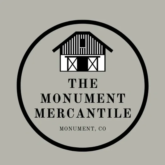 Logo for The Monument Mercantile featuring a barn illustration and text indicating location in Monument, Colorado.
