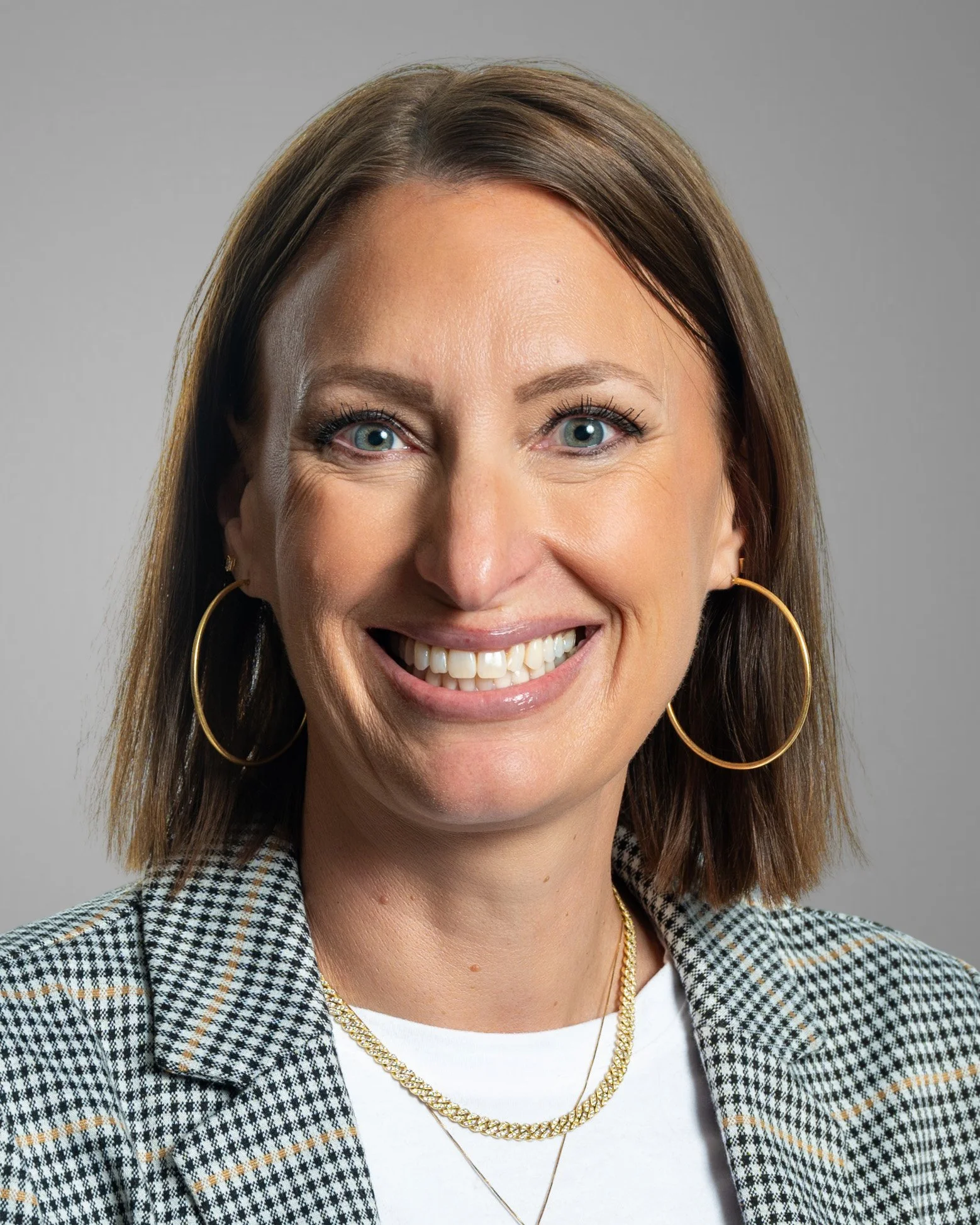 Smiling woman with long brown hair wearing a brown sweater