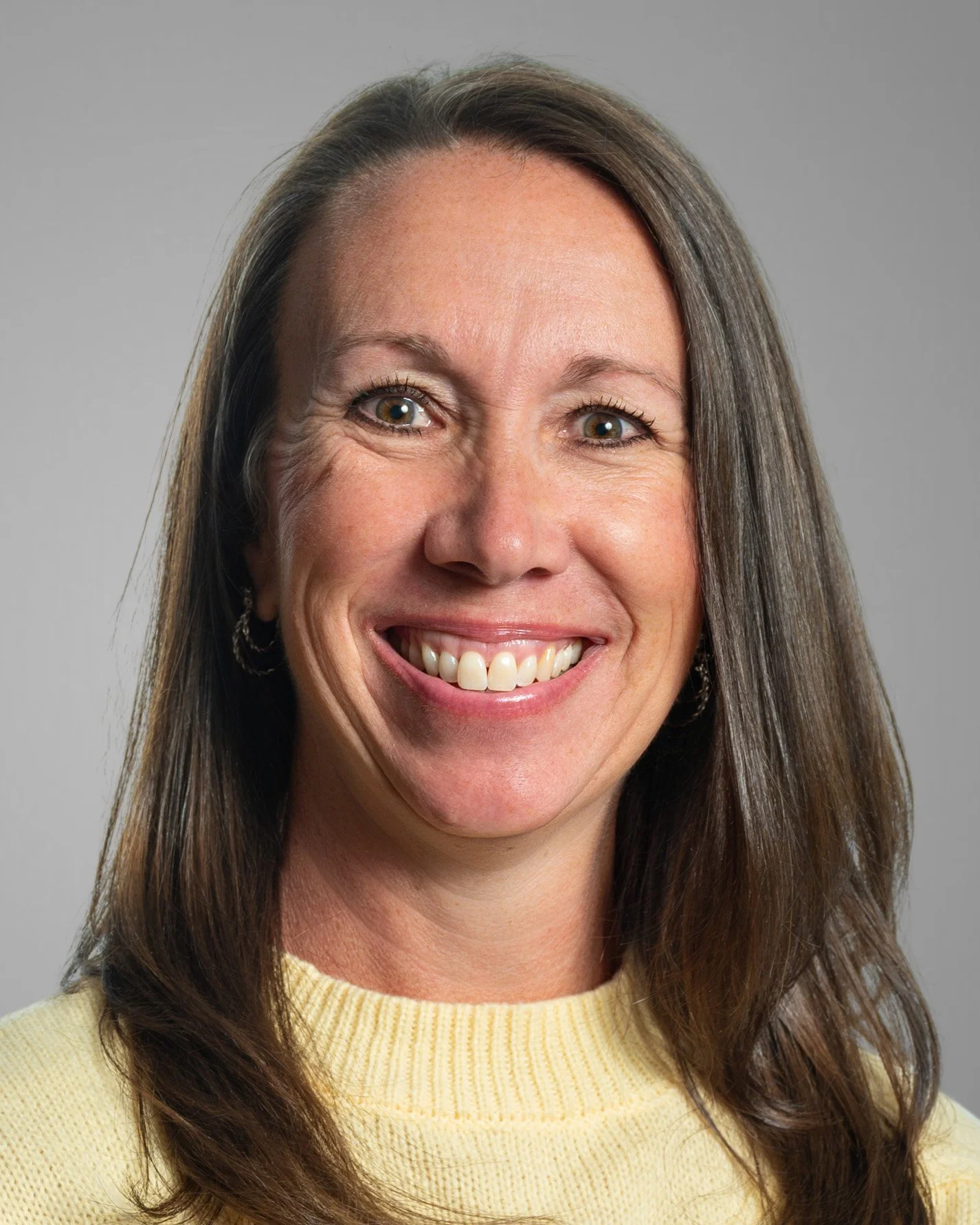 Smiling person wearing a denim jacket against a white background.