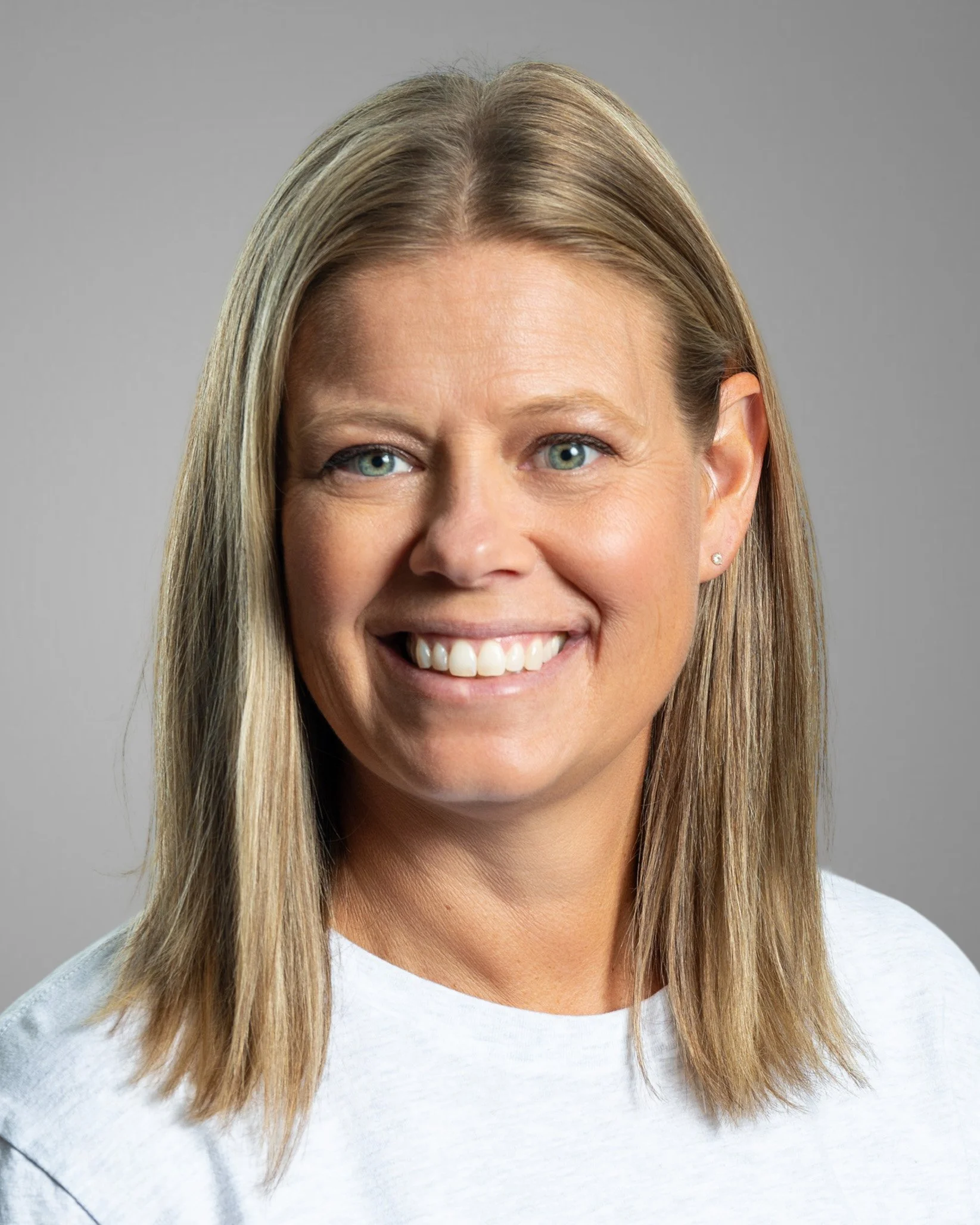 Smiling woman with blonde hair wearing a black shirt against a white background.