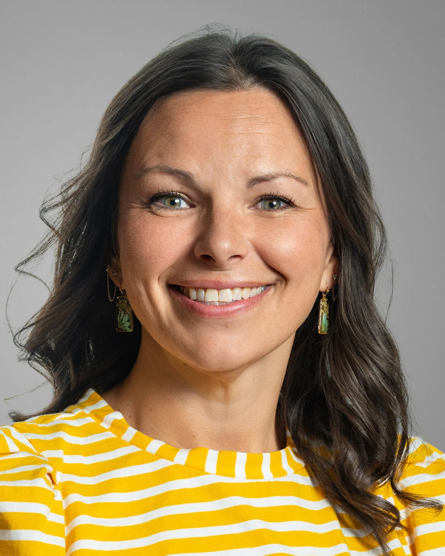 Smiling woman with brown hair wearing a floral blouse.