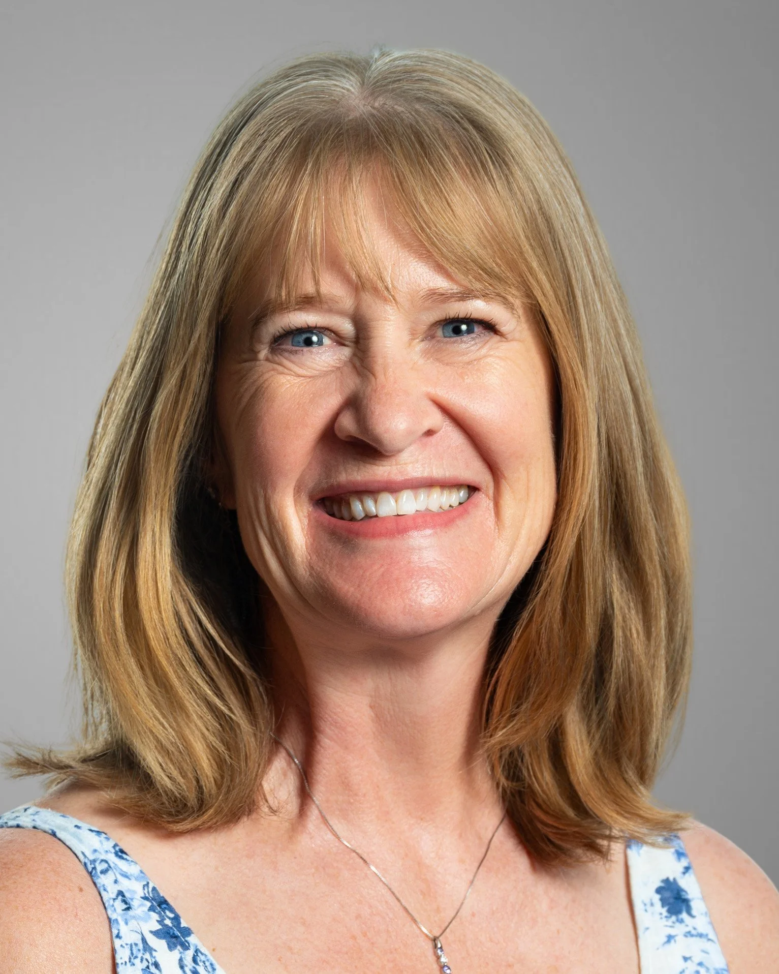 Smiling woman in a blue shirt against a white background.