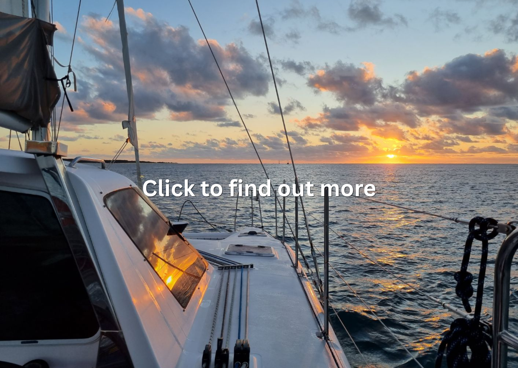 A boat sailing on the ocean at sunset, with the sky filled with clouds and the sun near the horizon.
