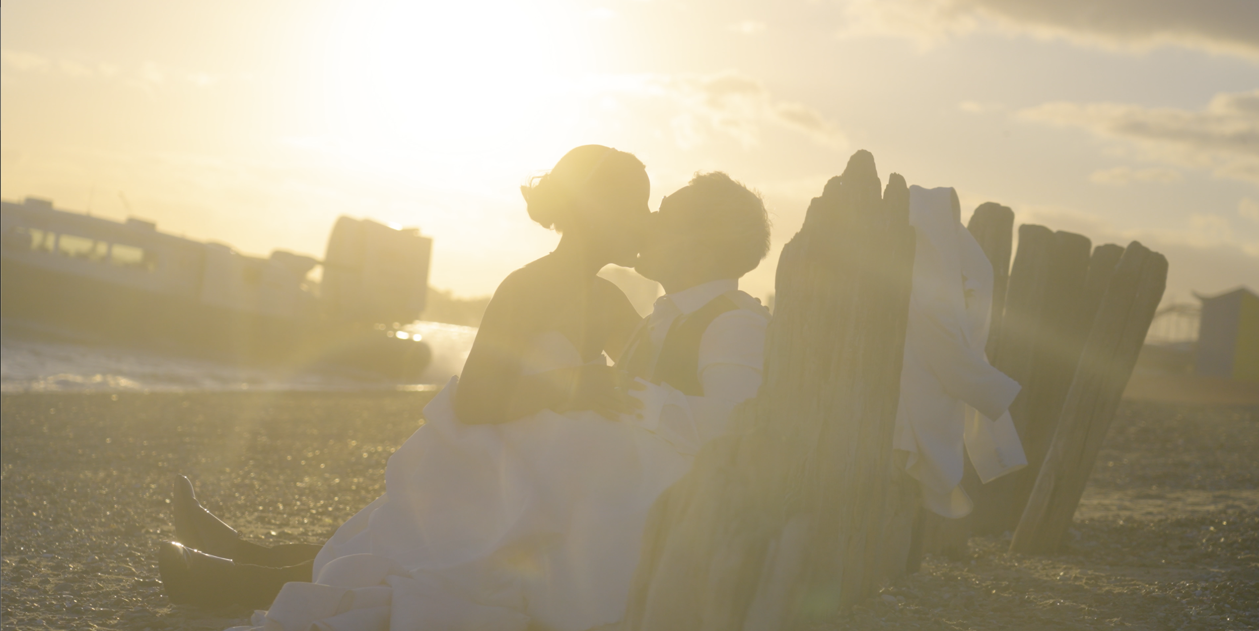 A couple sitting on beach chairs sharing a kiss at sunset