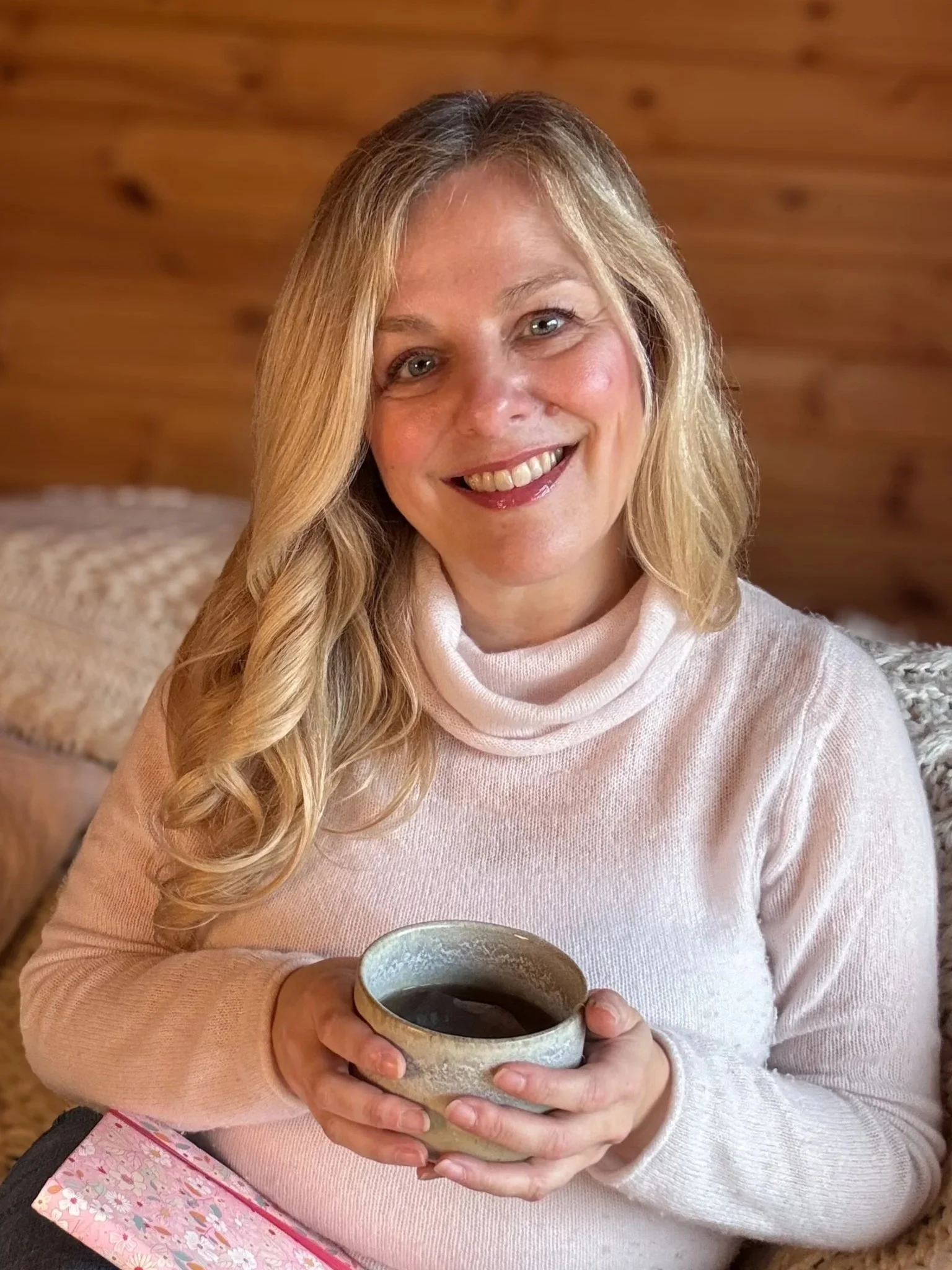 arah Pritchard, a Soma Soul® Somatic Therapist and an ISMETA registered Master Somatic Movement Therapist, smiling in her warm, wood-paneled somatic therapy cabin in Shrewsbury.
