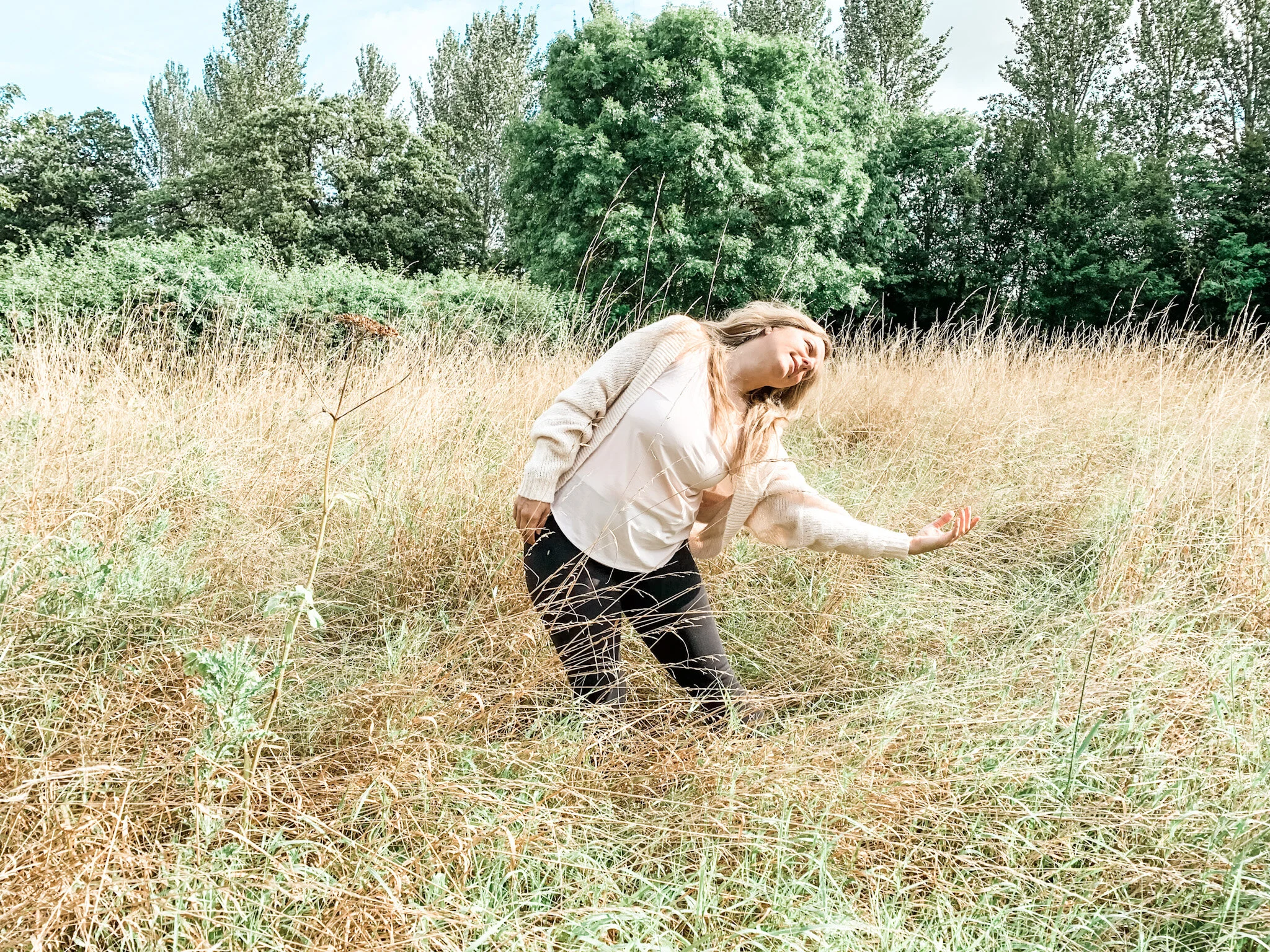 Sarah Pritchard, ISMETA MSMT/MSME, performing flowing somatic movement outdoors in a grassy field, reflecting her holistic movement ethos.