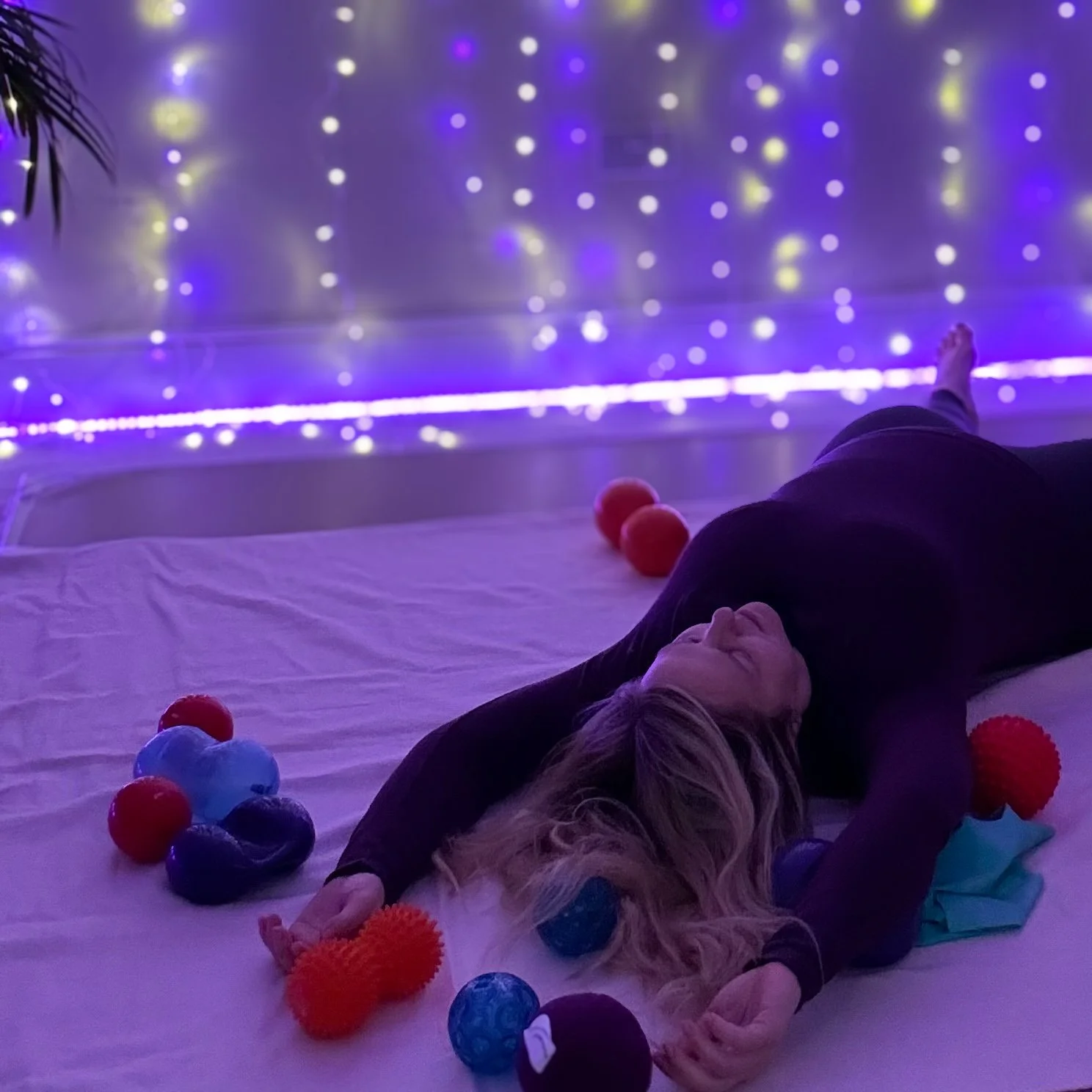 Sarah Pritchard lying on a mat using Franklin Method balls to release back and shoulder tension offering her relaxation class at Cool Pilates Birmingham.