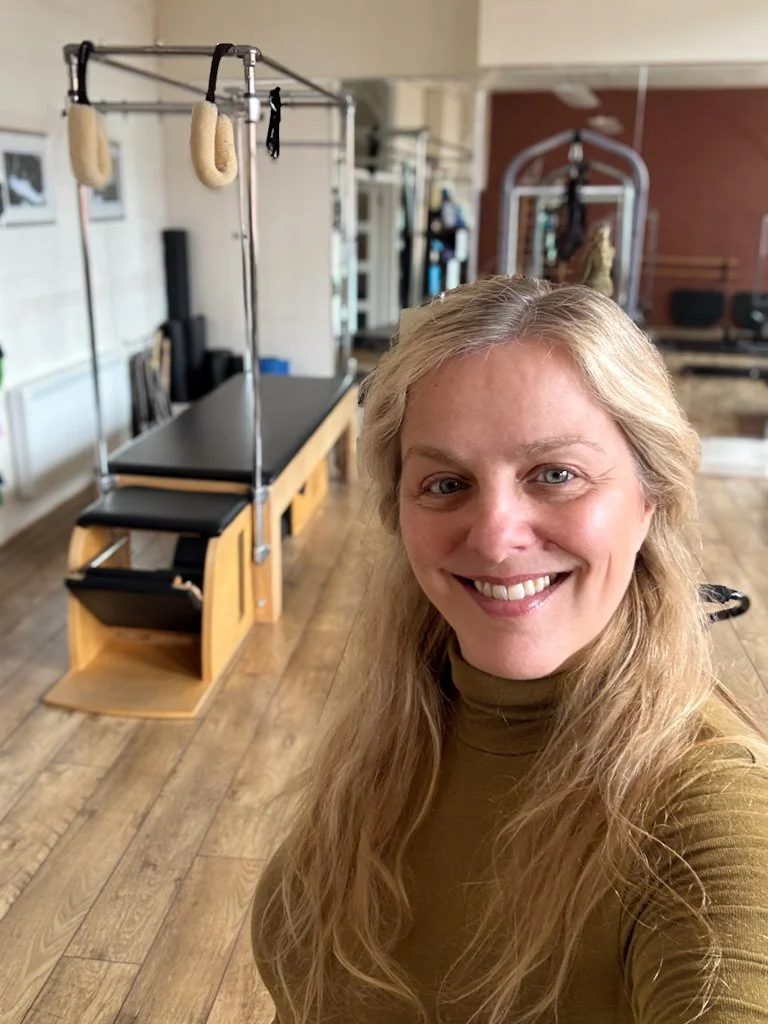Sarah Pritchard Comprehensive and Remedial Pilates teacher at Cool Pilates studio Jewellery Quarter Birmingham with Pilates studio equipment and wooden flooring.