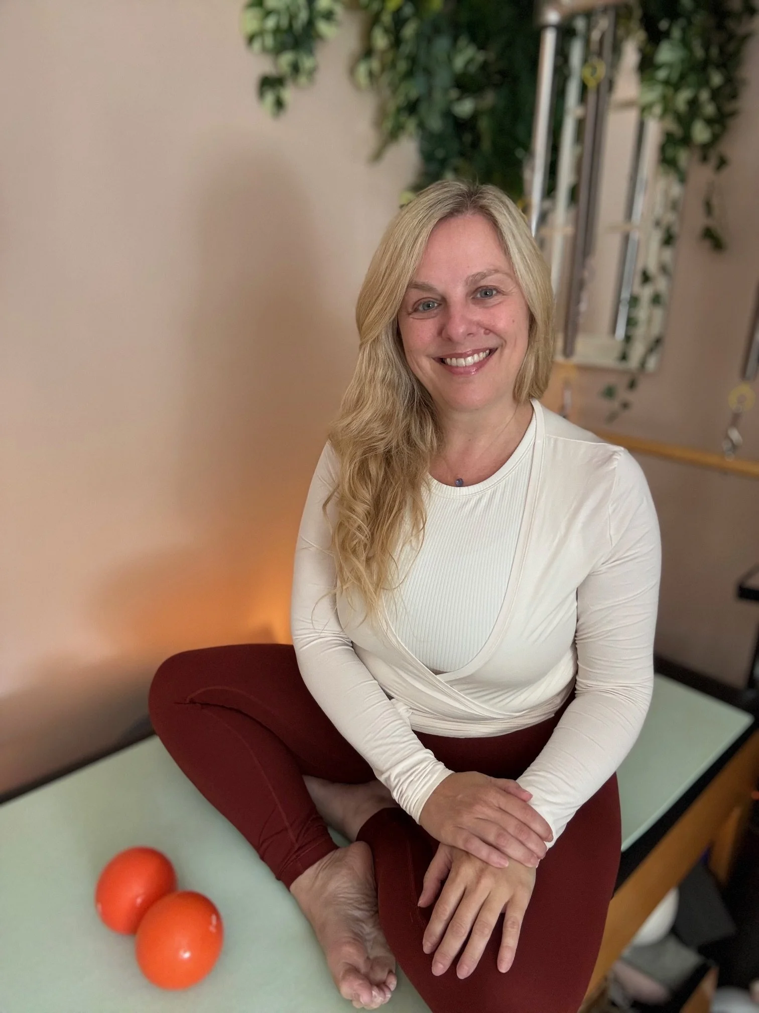 Sarah Pritchard, Master Somatic Movement Therapist and MSMT/MSME Educator, seated with orange Franklin Method balls for nervous system regulation and fascia release in somatic pilates practice