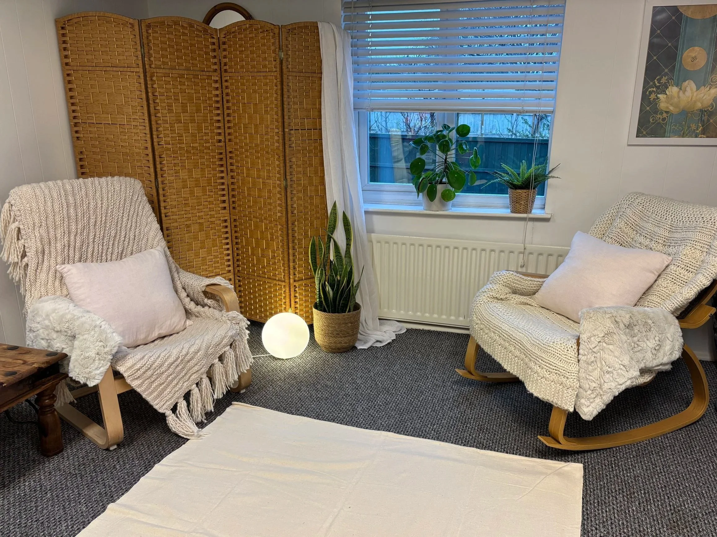 Cozy somatic therapy clinic with natural wood chairs, woven blankets, and soft lighting for 1:1 movement sessions